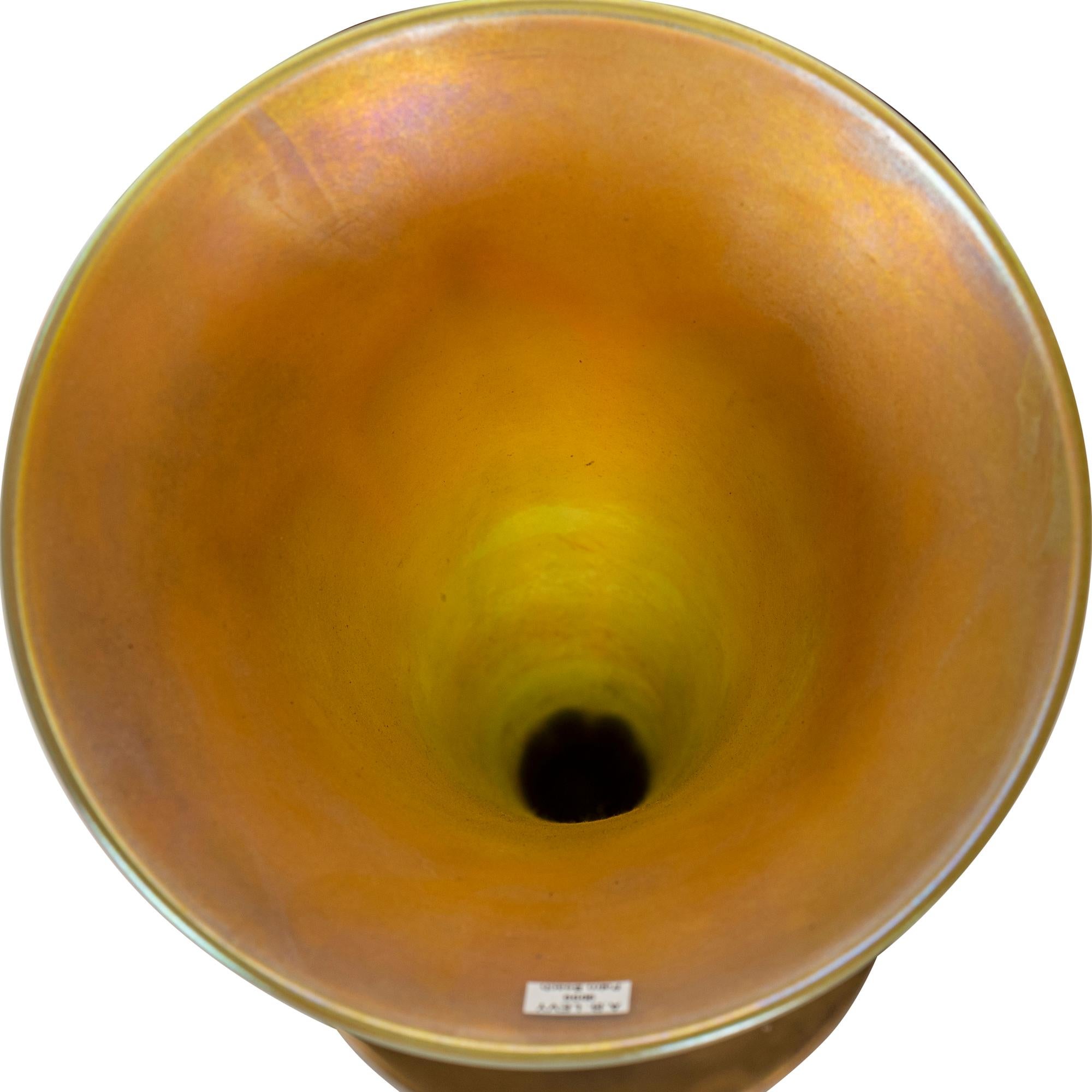 Tiffany-Studios
um 1900
Fein dekorierte Vase aus vergoldeter Bronze und Tiffany-Favril-Glas, trompetenförmig, Glaseinsatz mit grünem Blattmotiv und Goldbändern auf opalfarbenem Grund, goldfarben ausgekleidet
graviert L.C.T. Favrile, Sockel