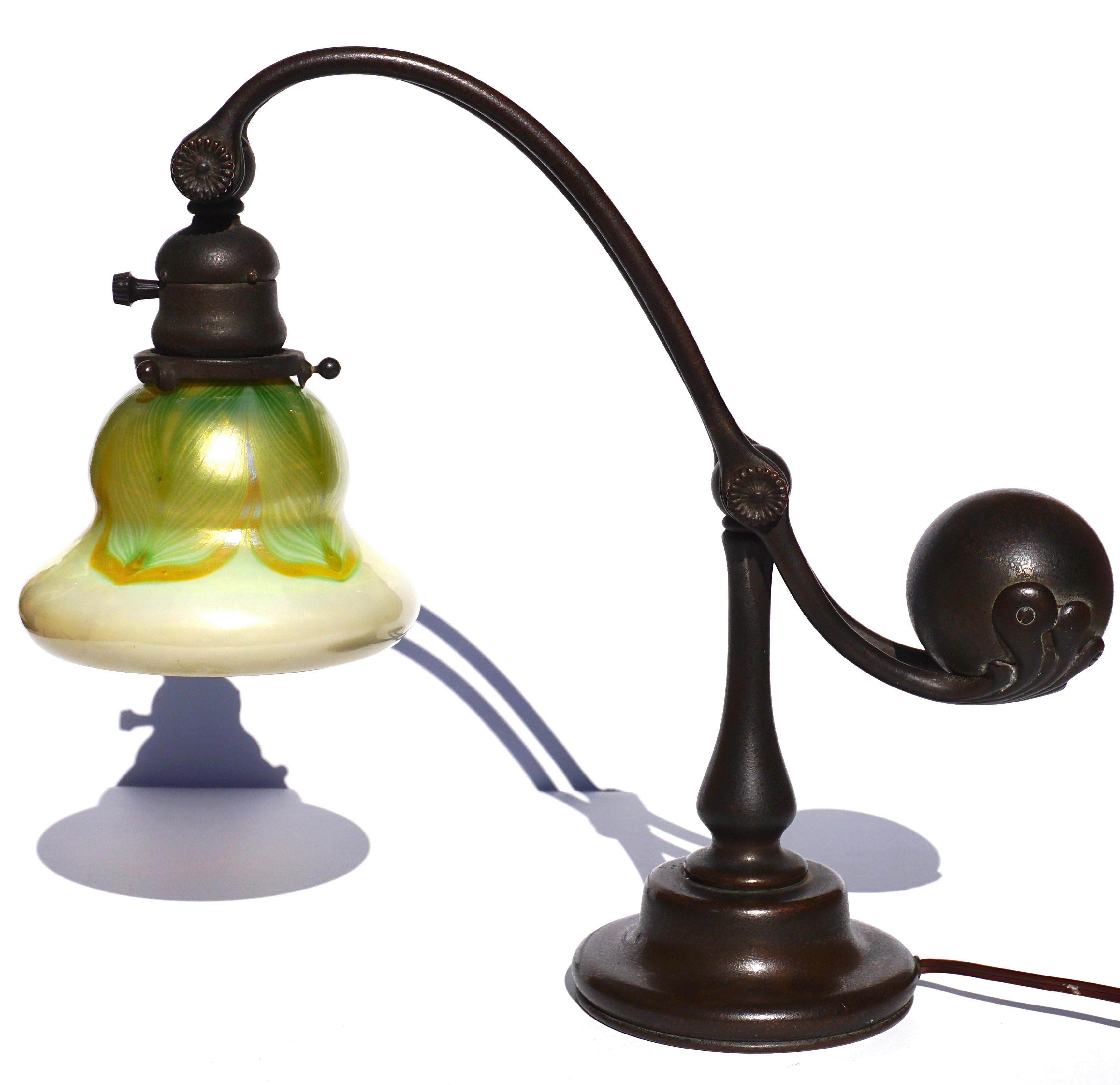 Tiffany Studios counter balance bronze and pulled feather Favrile art glass shade table or desk lamp.

A Tiffany Studios New York counterbalance bronze desk lamp having bronze adjustable two arm body with ball balance. It features a Tiffany