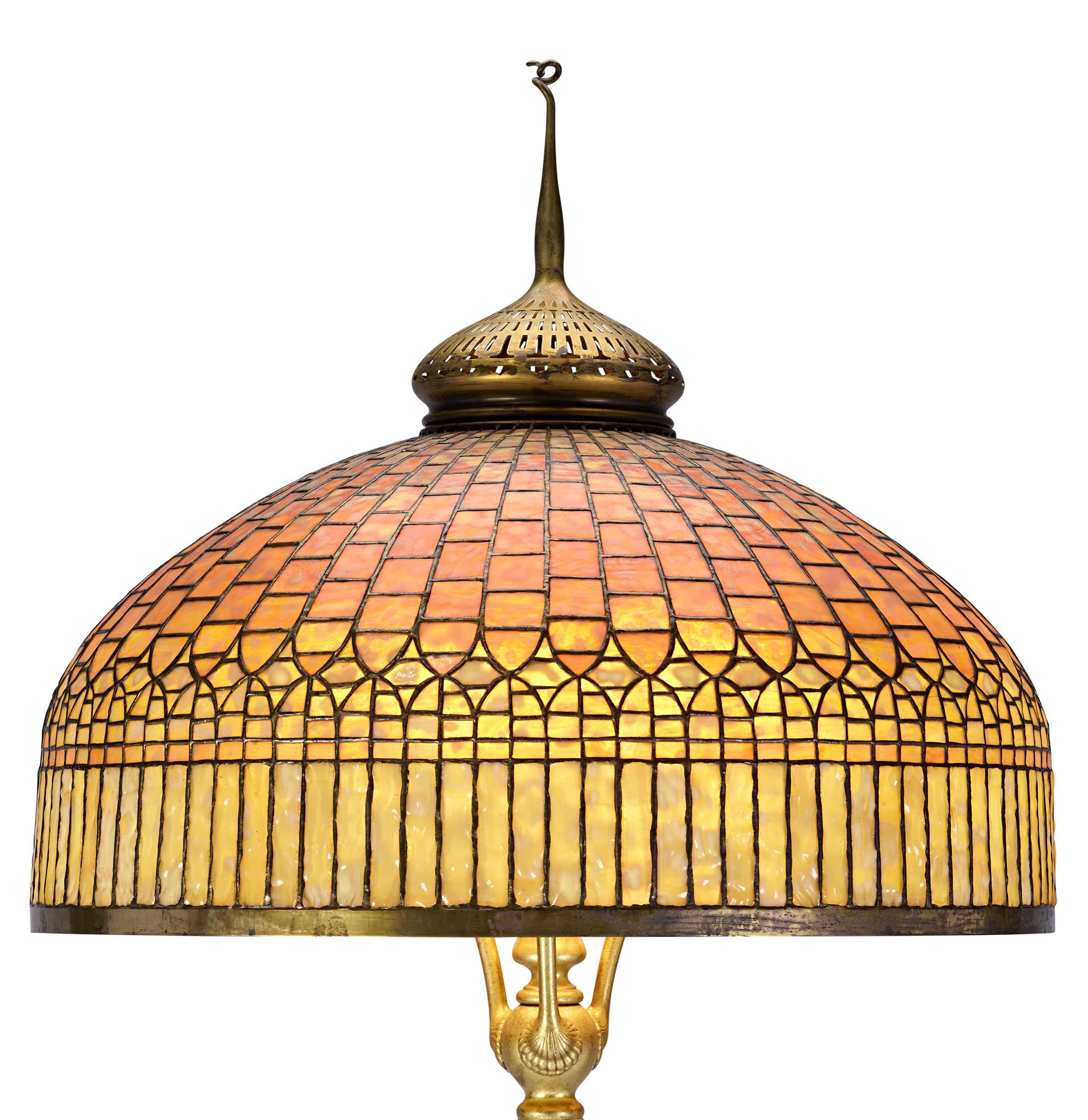 This important Tiffany Studios floor lamp features a splendid 24-inch Curtain Border shade and its original patinated bronze base. Among Tiffany’s most iconic designs, this monumental shade cleverly evokes the timeless glamour of a fringed