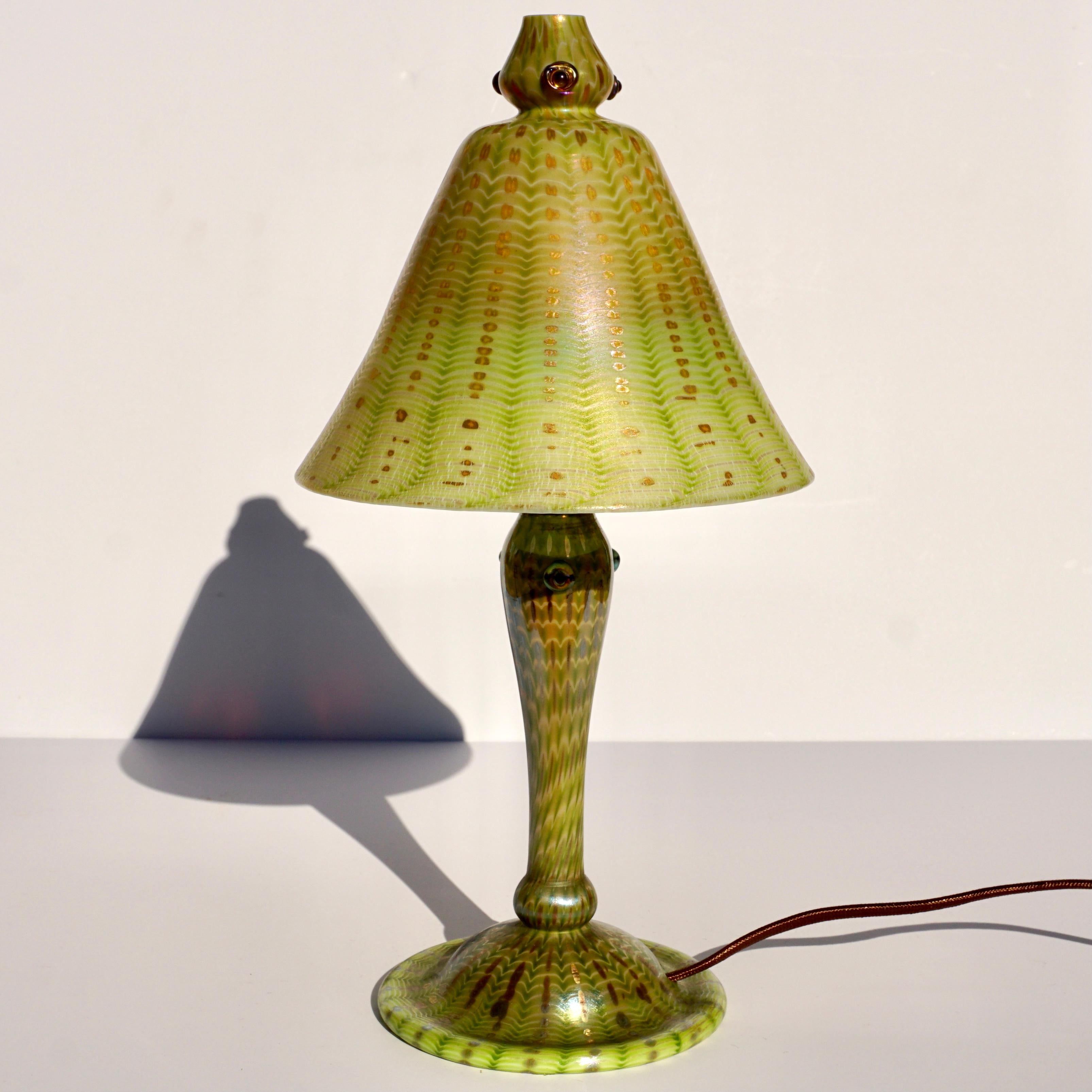 Tiffany Favrile Arabian Lampe. Jugendstil, um 1910 

Arabische Tiffany-Lampe mit Schirm und Sockel aus geblasenem Glas. Der Schirm ist mit einem grün schillernden Reißverschlussmuster vor einem wellenförmigen goldgelben Hintergrund verziert. Die