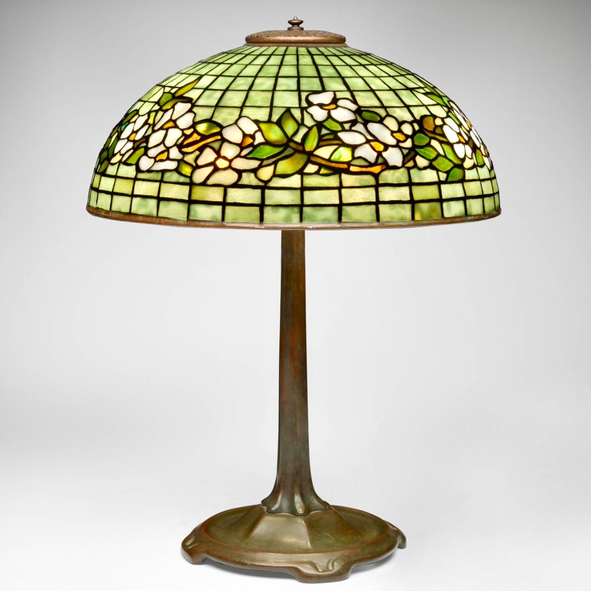 Tiffany Studios Art Glass and Bronze Dogwood Table Lamp
Dogwood Band table lamp
New York, USA, c. 1910
Leaded glass, Patinated bronze
Height: 21.5 Inches X 16 Inches Diameter (55 × 41 cm)
Lamp features a Library Standard base.

Impressed to tag on