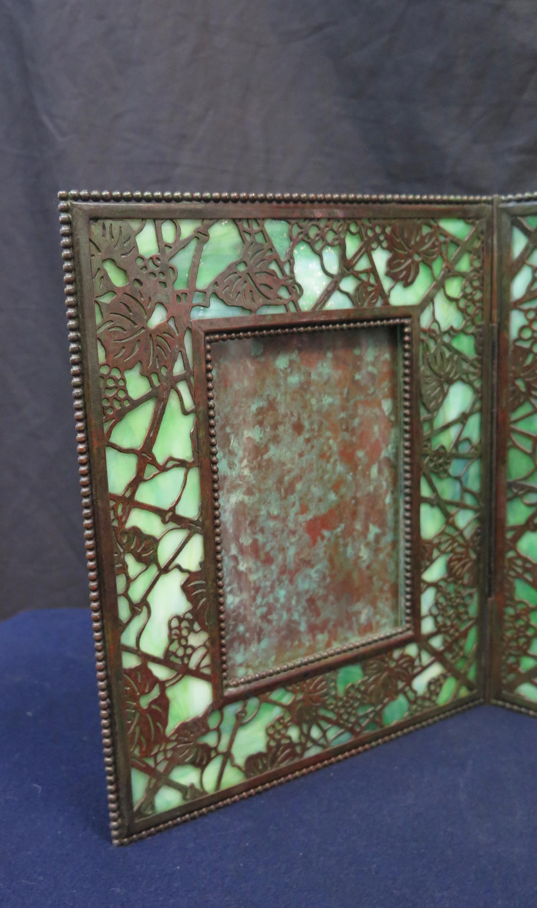 This beautifully preserved vintage Tiffany Studios side by side double bronze and glass photo frame is designed in the grapevine motif and dates from the early 20th century. Patinated bronze grapevine pattern is showcased overlaying green favrile
