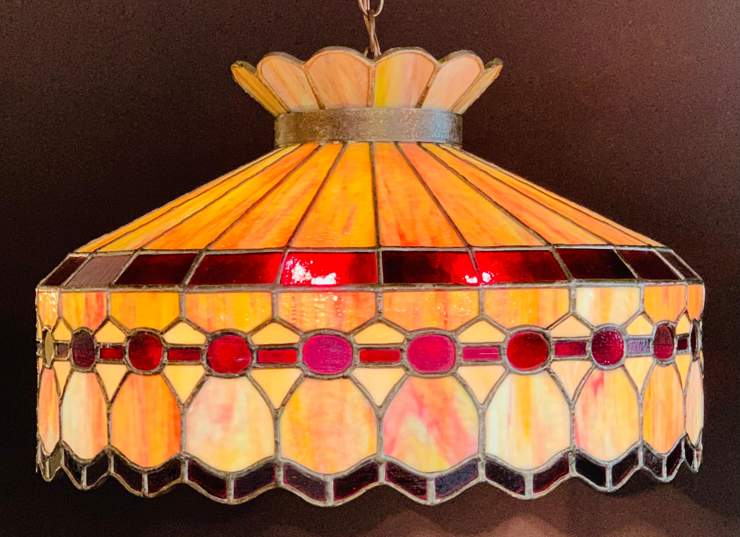 A stunning midcentury Tiffany Studios fashioned burgundy and off- white / light pink color fused glass pendant or chandelier with bronze inlay. The chandelier features a crown shaped top and a horizontal band leaded glass panel design. The hand