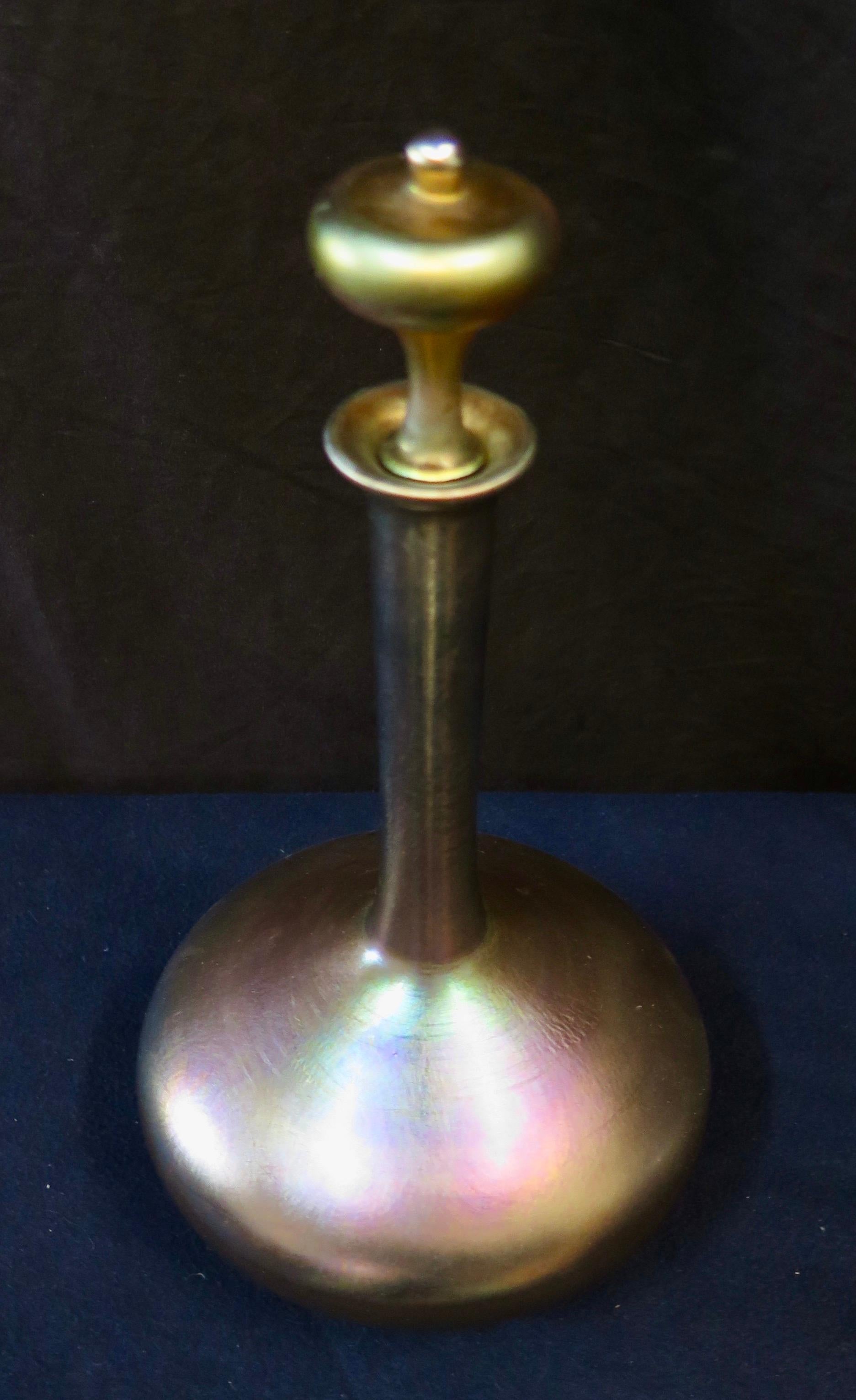 This vintage early 20th century favrile art glass decanter was produced by the Tiffany Studios, New York. The iridescent decanter features a long slender neck that flows down to a large bulbous shape base. An elegant handmade stopper marked 957