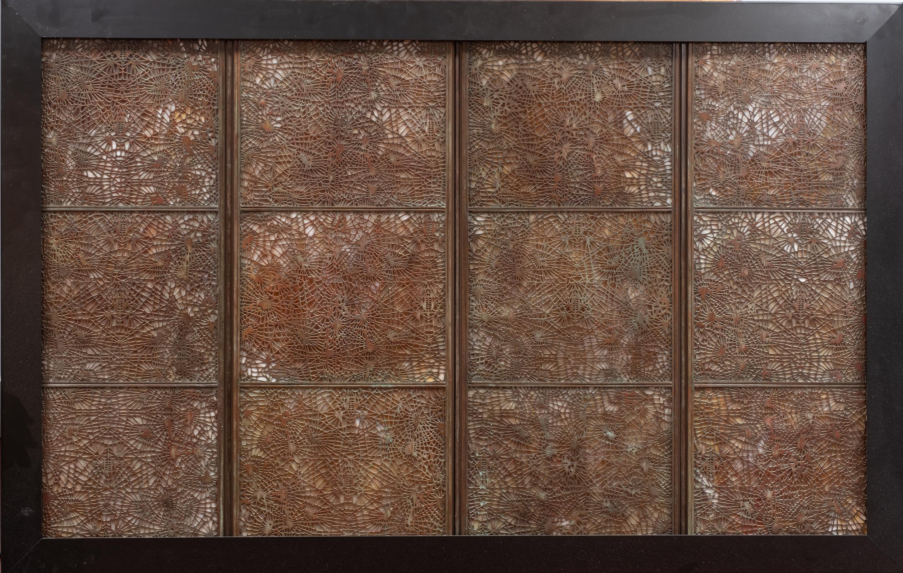 Studios Tiffany, New York, (1878-1930). Ce grand paravent à quatre panneaux en verre favrile et bronze des Studios Tiffany, au motif d'aiguilles de pin, a été monté en qualité galerie dans une boîte à lumière murale en métal noir. Pas de marque de