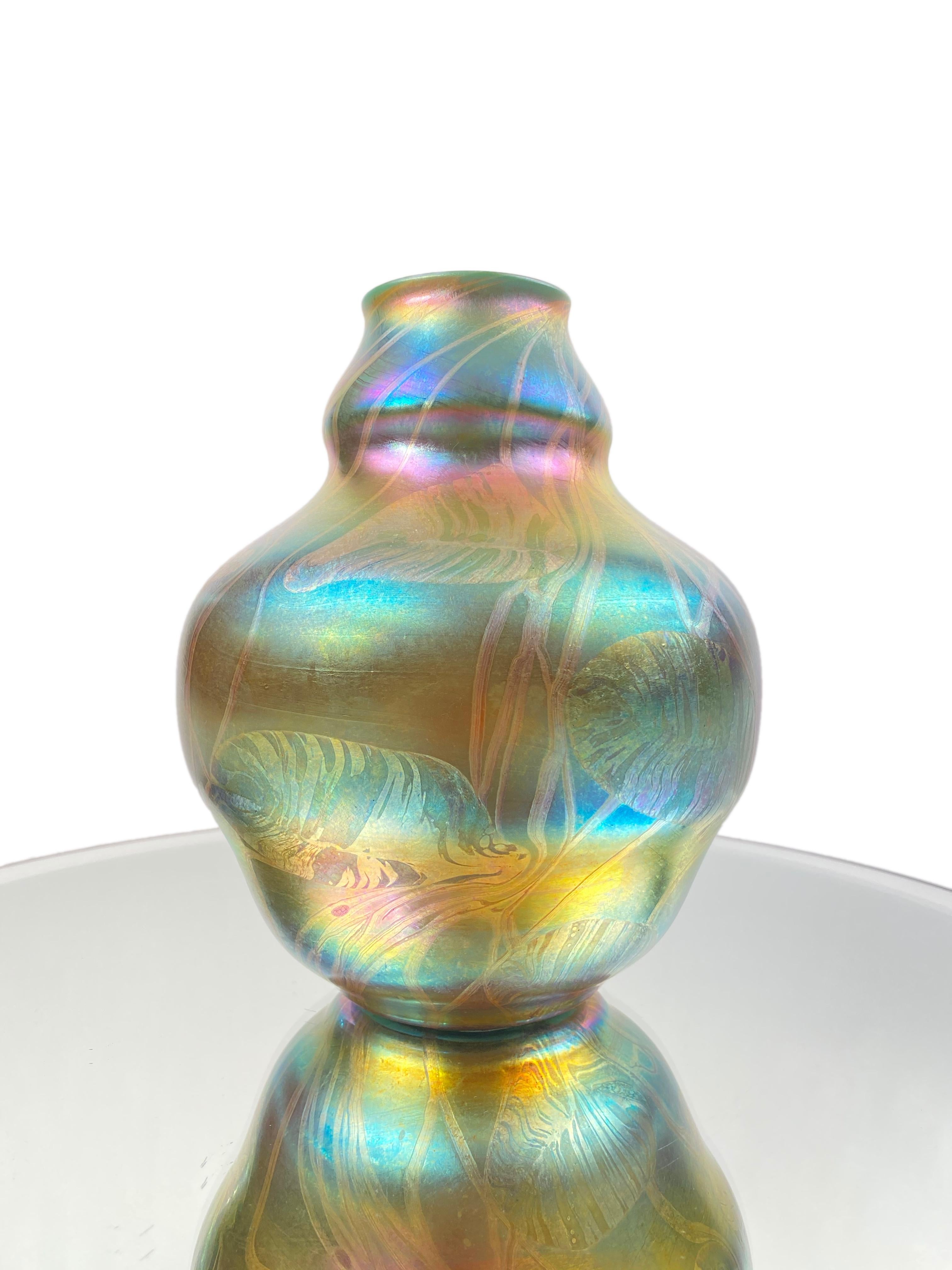 A fine and rare American Art Nouveau blown Tiffany Favrile “Leaf & Vine” vase by, Tiffany Studios decorated with highly iridescent and beautifully detailed leaf and vine decoration against a heavily iridized blue background. The vase is signed,