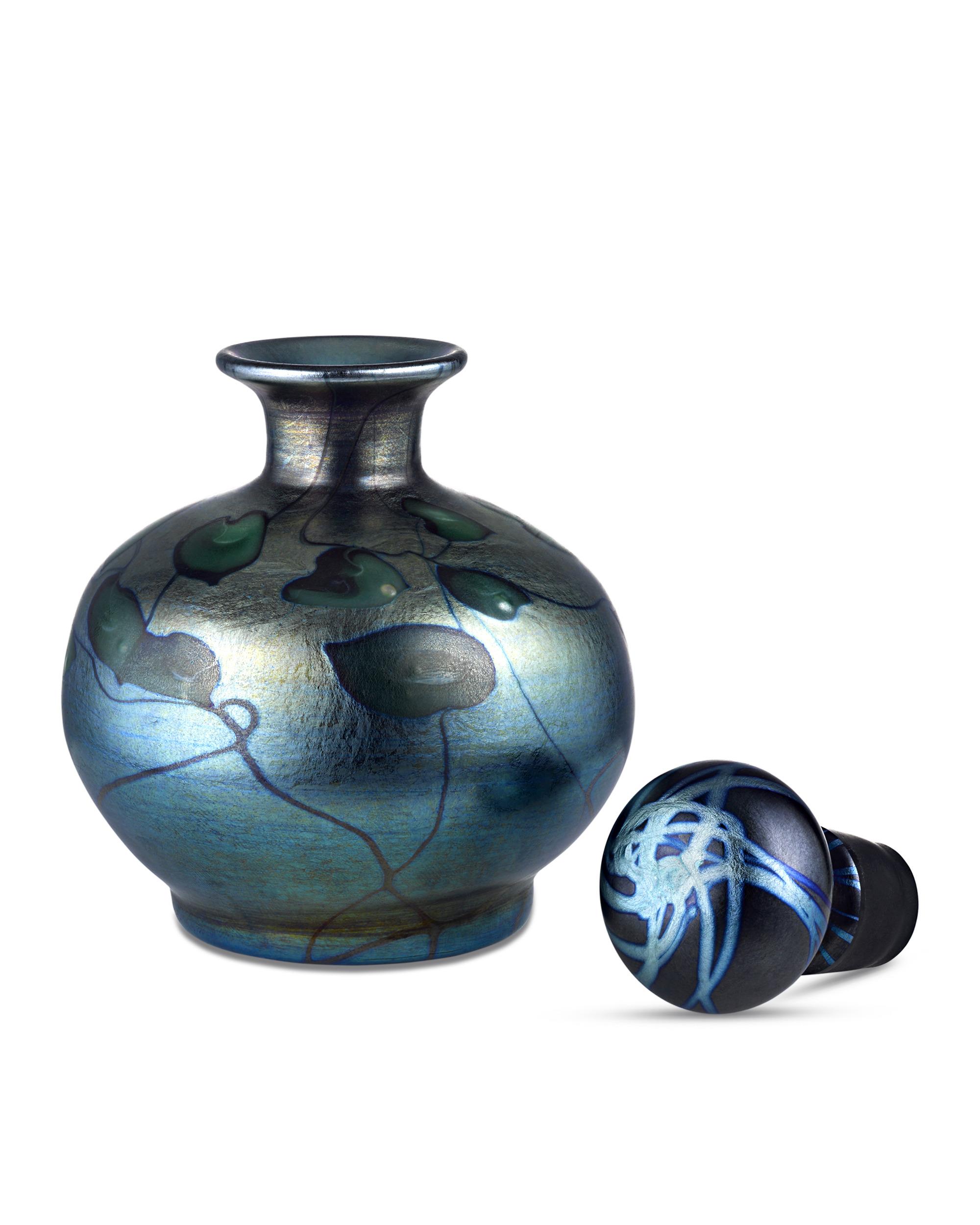 This sophisticated Tiffany Studios Favrile glass perfume vessel features the desirable Heart and Vine pattern. The iridescent blue ground is marked with green heart-shaped leaves, creating a highly dimensional effect. The lustrous shine of the