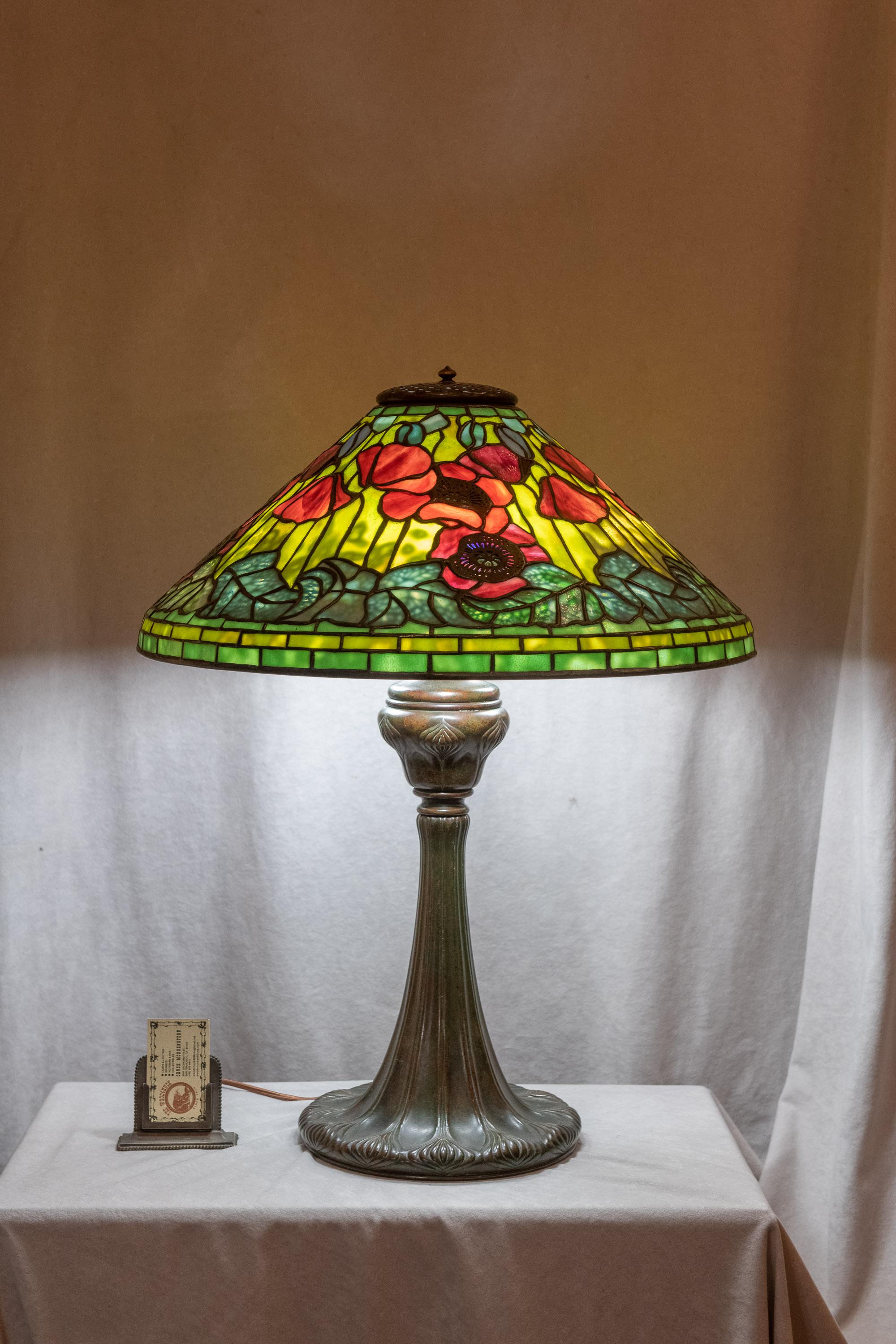 This spectacular lamp was one of Tiffany's best. The poppies are rich red with Fine Tiffany glass. The interior filagree metalwork behind the leaves give the appearance of veins to those leaves. The shade is remarkable condition. We had to hunt to