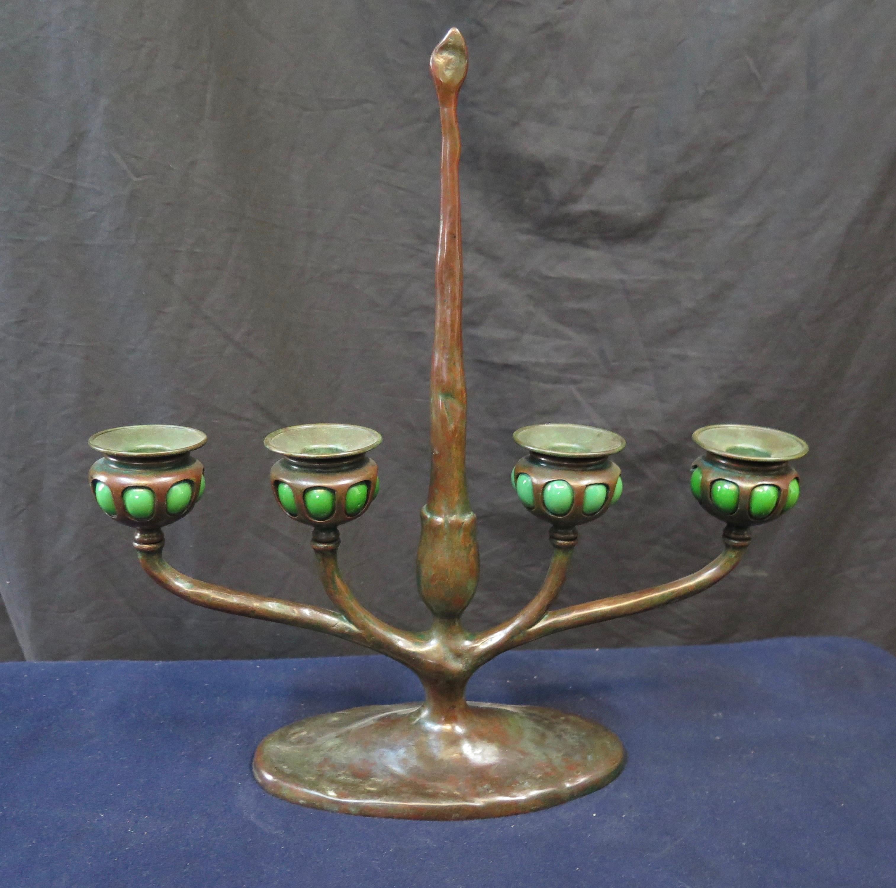 This vintage patinated bronze candelabra was made by the Tiffany Studios, New York & dates from the early 20th century. The decorative four place candelabra is designed with blown out green glass candle cups. Each candle cup retains an original