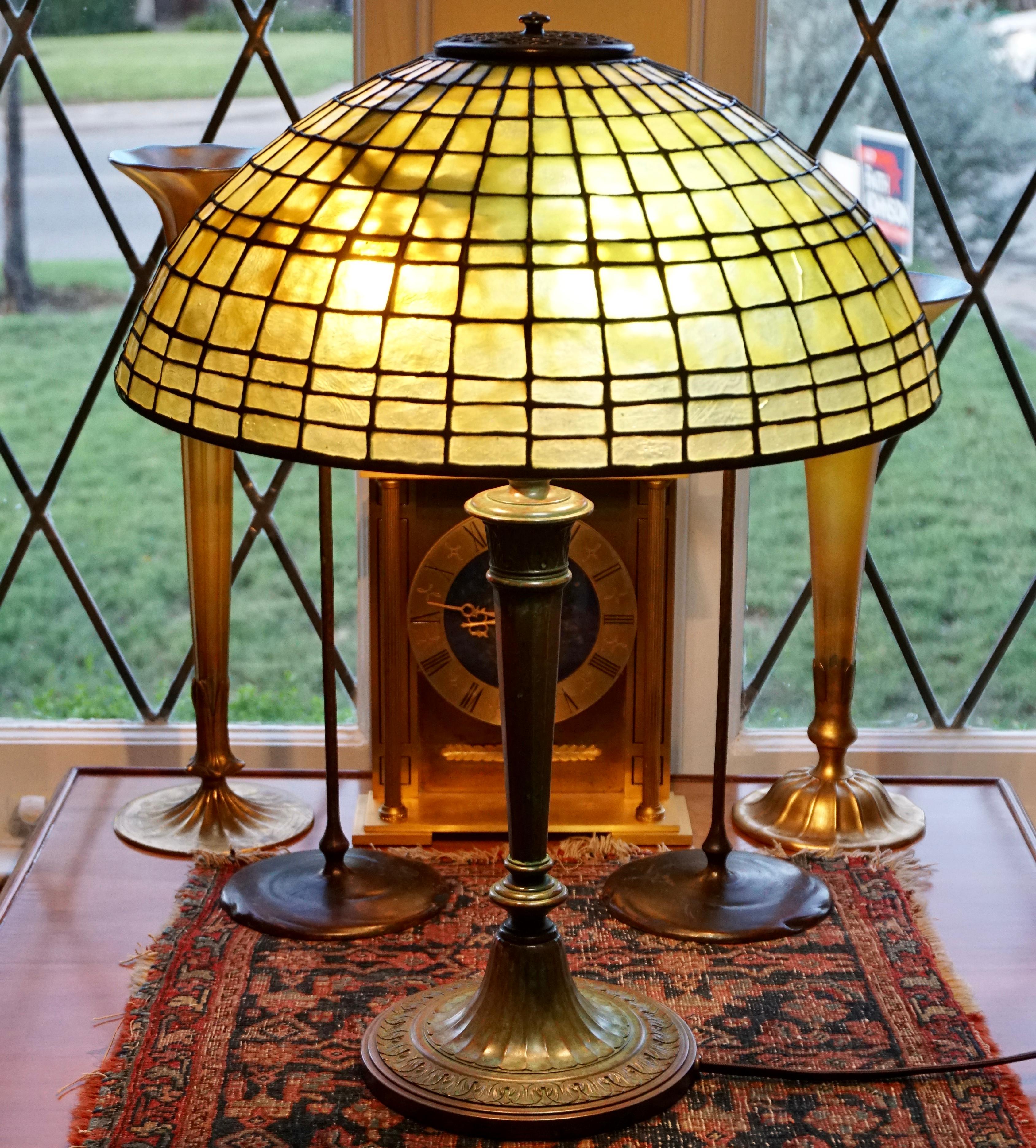 Tiffany Studios New York Art Nouveau Art Deco, circa 1910 bronze and lead glass desk or table lamp. Green unlit and yellow lit diachronic mottled lead glass shade. Sitting on a early bronze neoclasssic lamp base with 3-arm swirling lights with