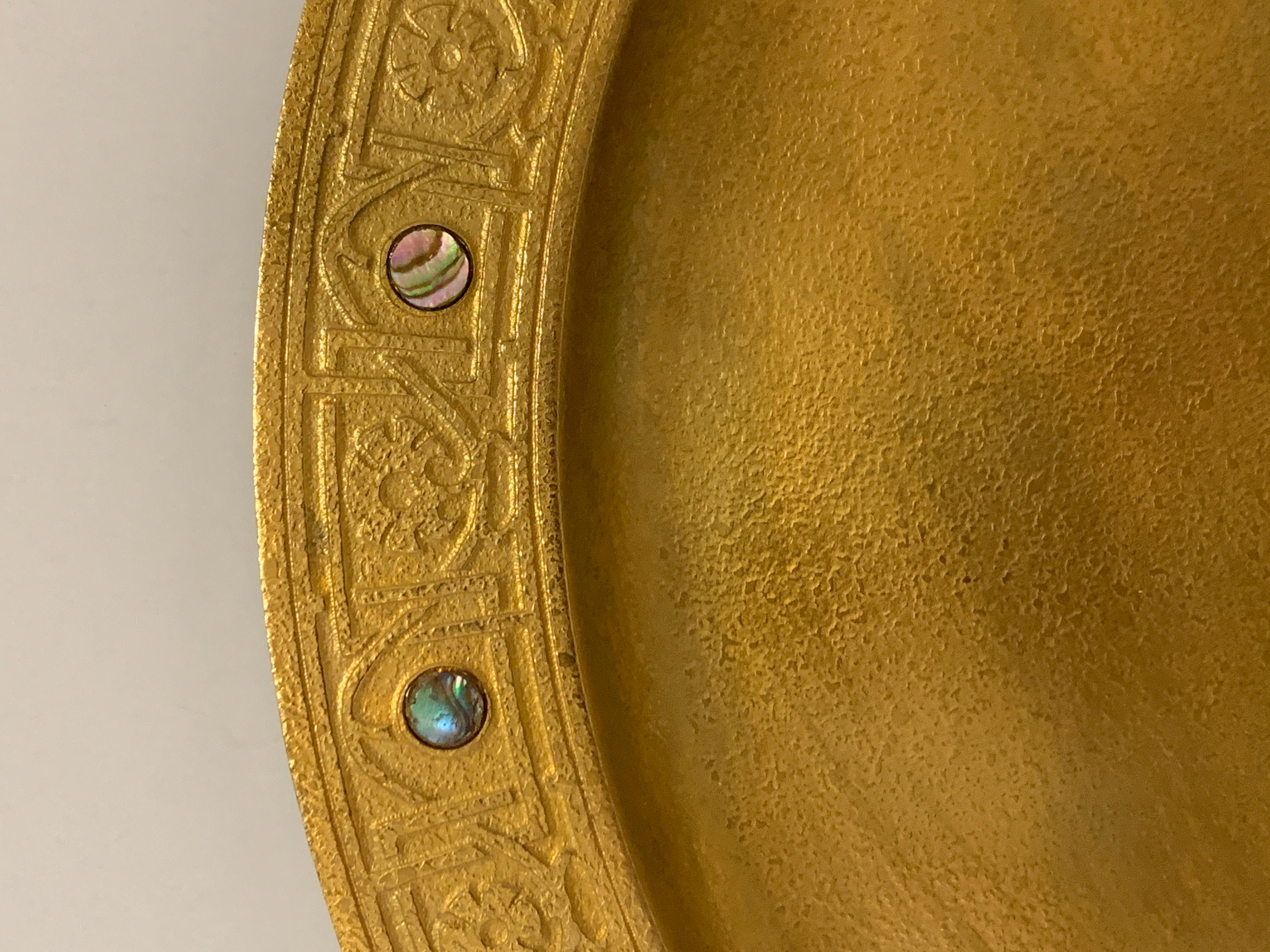 A signed Tiffany Studios gilt doré bronze charger inlaid on the rim with abalone insets. Features a nice rim design as well. Marked on the base with the number 1730. It is approx 12 inches in diameter. Overall good age appropriate condition with
