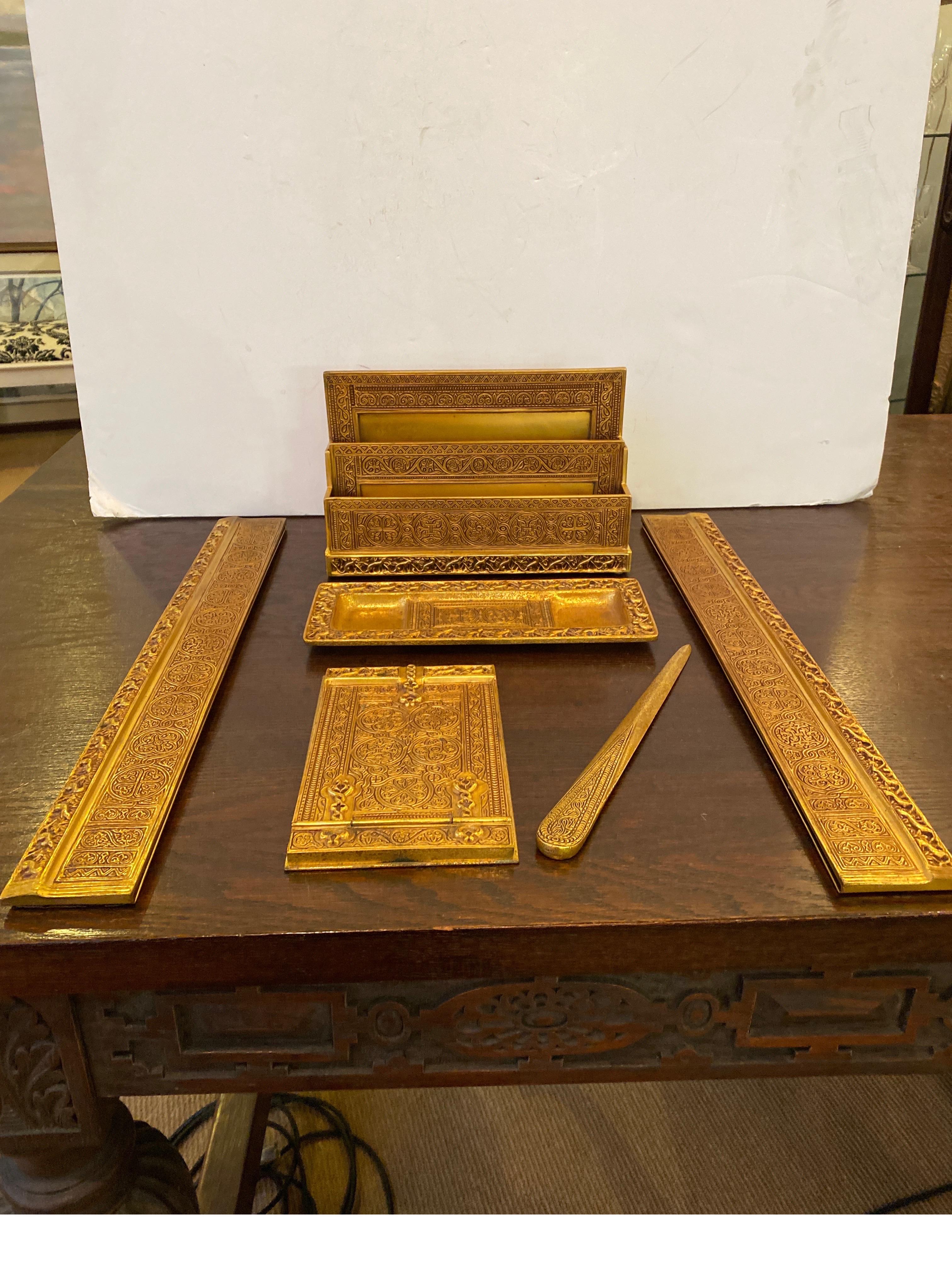 Tiffany Studios circa 1915 desk set, comprising a pair of blotter ends, a letter rack, notepad, pen tray, letter opener. 
Letter rack, calendar frame, double inkstand, notepad, pen tray, paperweight, pen brush and letter opener each impressed