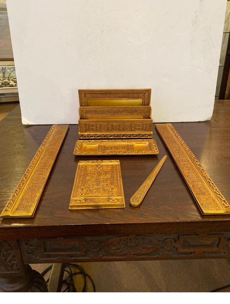 Tiffany Studios circa 1915 desk set, comprising a pair of blotter ends, a letter rack, notepad, pen tray, letter opener. 
Letter rack, calendar frame, double inkstand, notepad, pen tray, paperweight, pen brush and letter opener each impressed