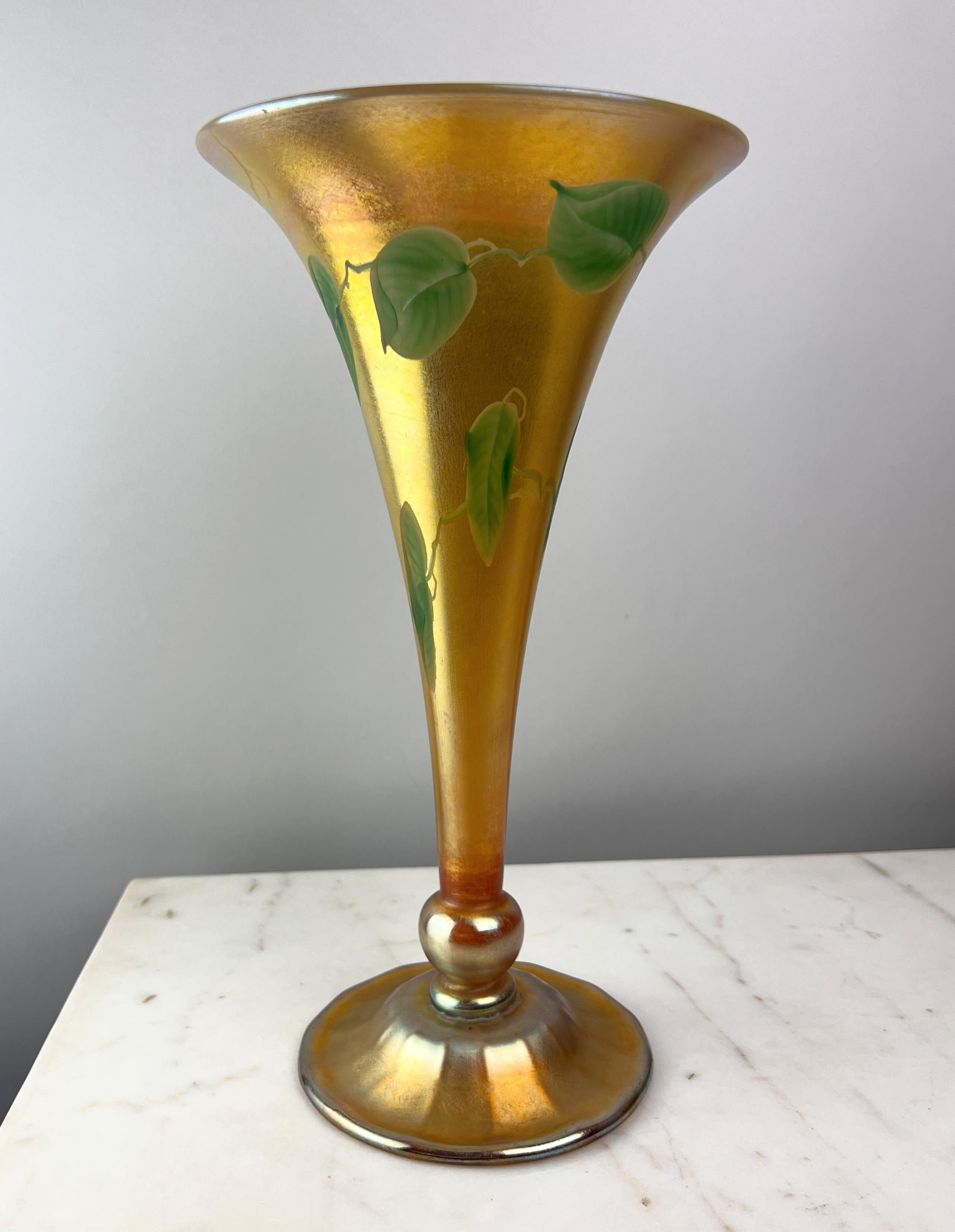 Voici un magnifique vase en Favrile Vine and Leaf de 1915 des Tiffany Studios, une incarnation étonnante de l'art novateur de Louis Comfort Tiffany et de sa maîtrise de la forme et de la couleur. Cette pièce exquise présente une silhouette