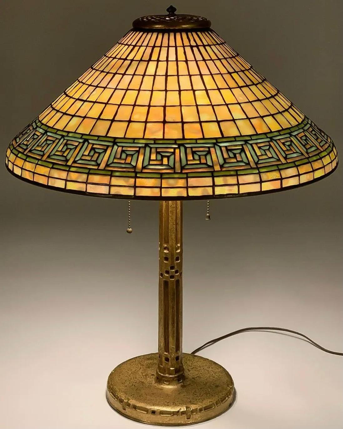 Tiffany Studios Greek key table lamp 
Circa. 1910. New York.

A large and beautiful 20-inch diameter conical leaded glass shade banded with Greek Key pattern over a geometric field and with typical thin gilt leading. Colors are mottled yellow,