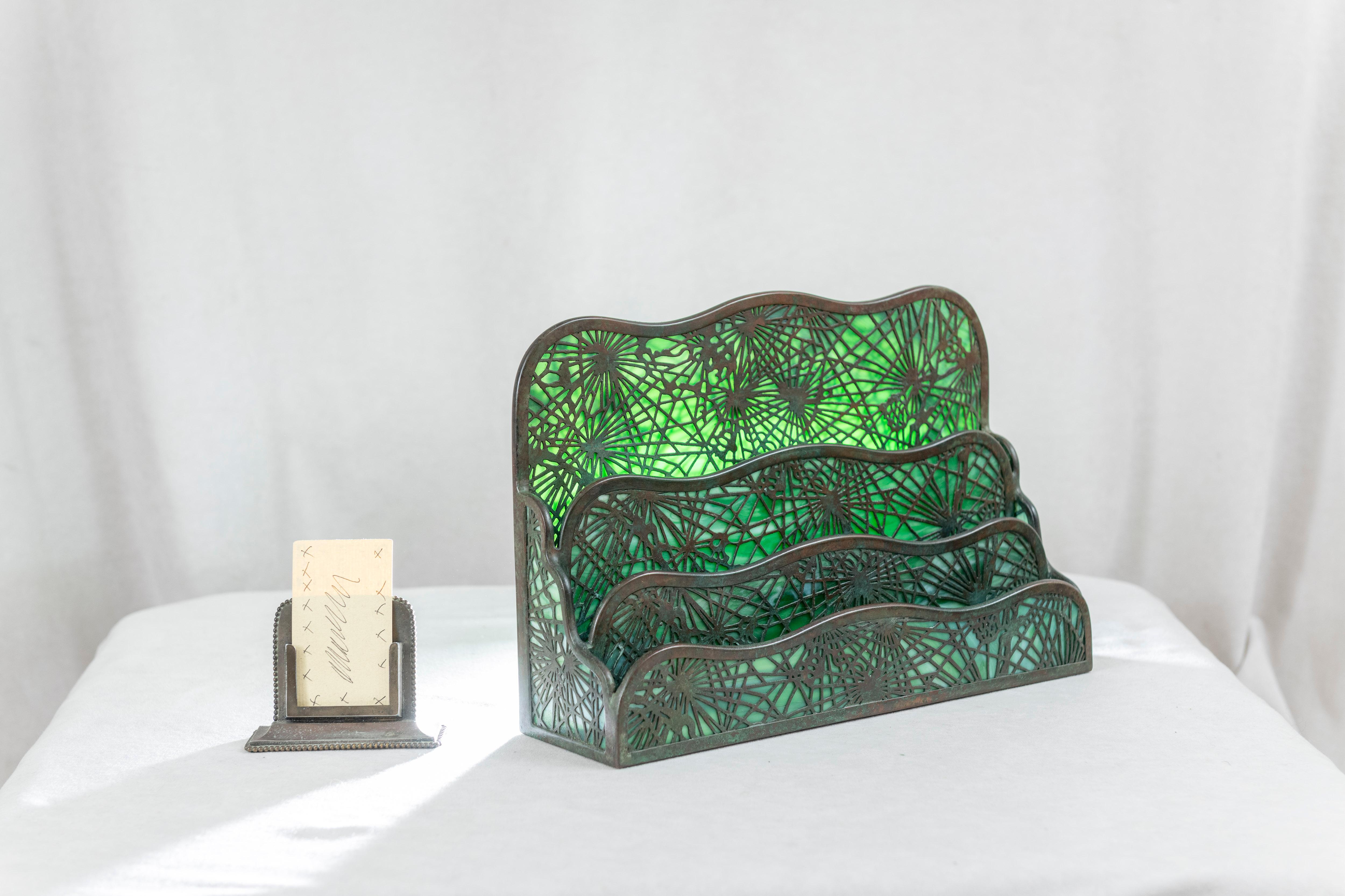  This beautiful and yet practical desk piece was made by the best we had here in the U.S., Tiffany Studios. Yes, the same man who made all those fabulous lamps. Using glass and metal overlay in a pine needle pattern, a letter rack is created. These