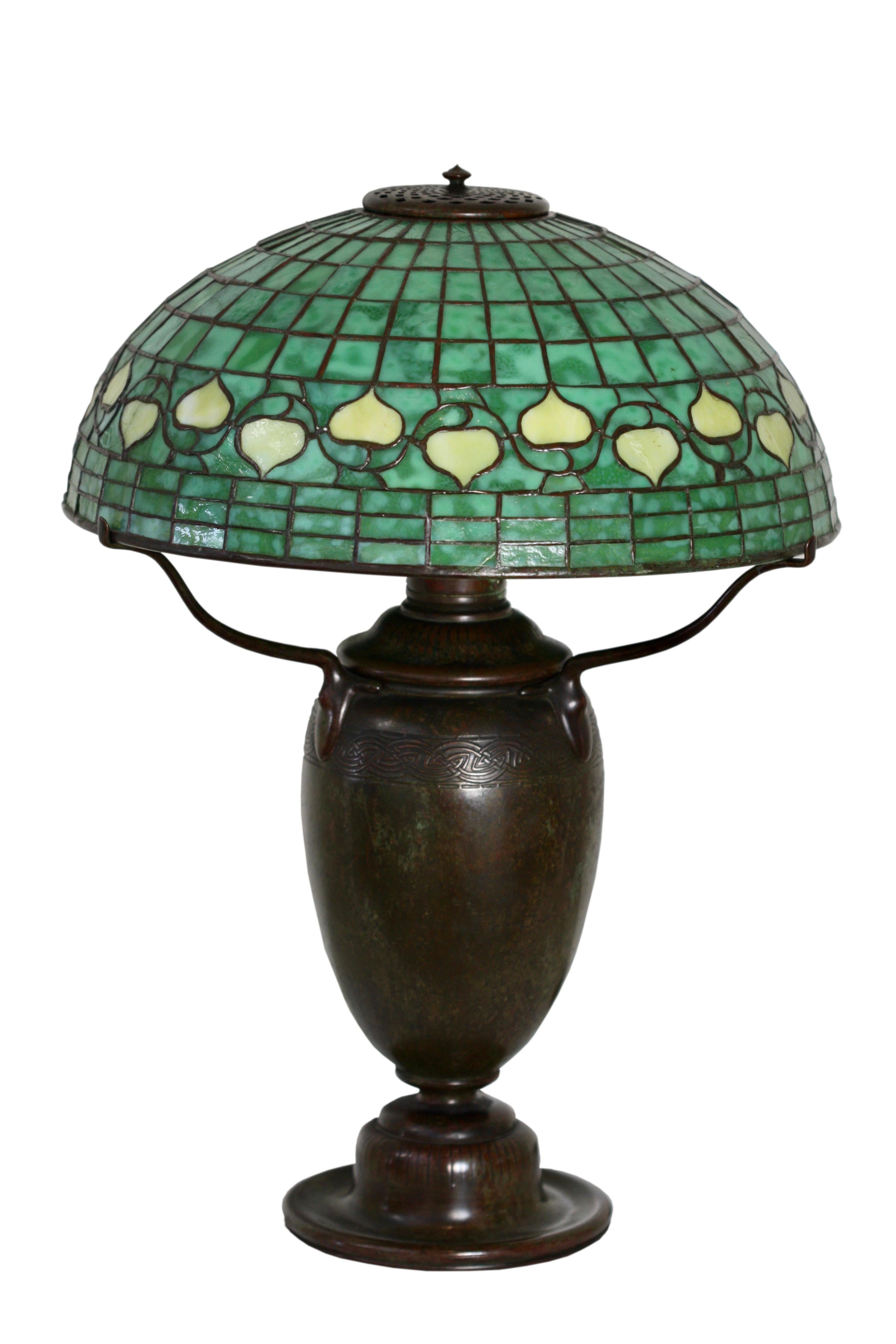 Studios Tiffany
Lampe de table « Vine Border » en verre plombé et bronze patiné, vers 1910
Sur une grande base en forme d'urne grecque avec trois bras de supports en forme d'araignée au-dessus d'une boîte à huile en forme d'urne, font-huile