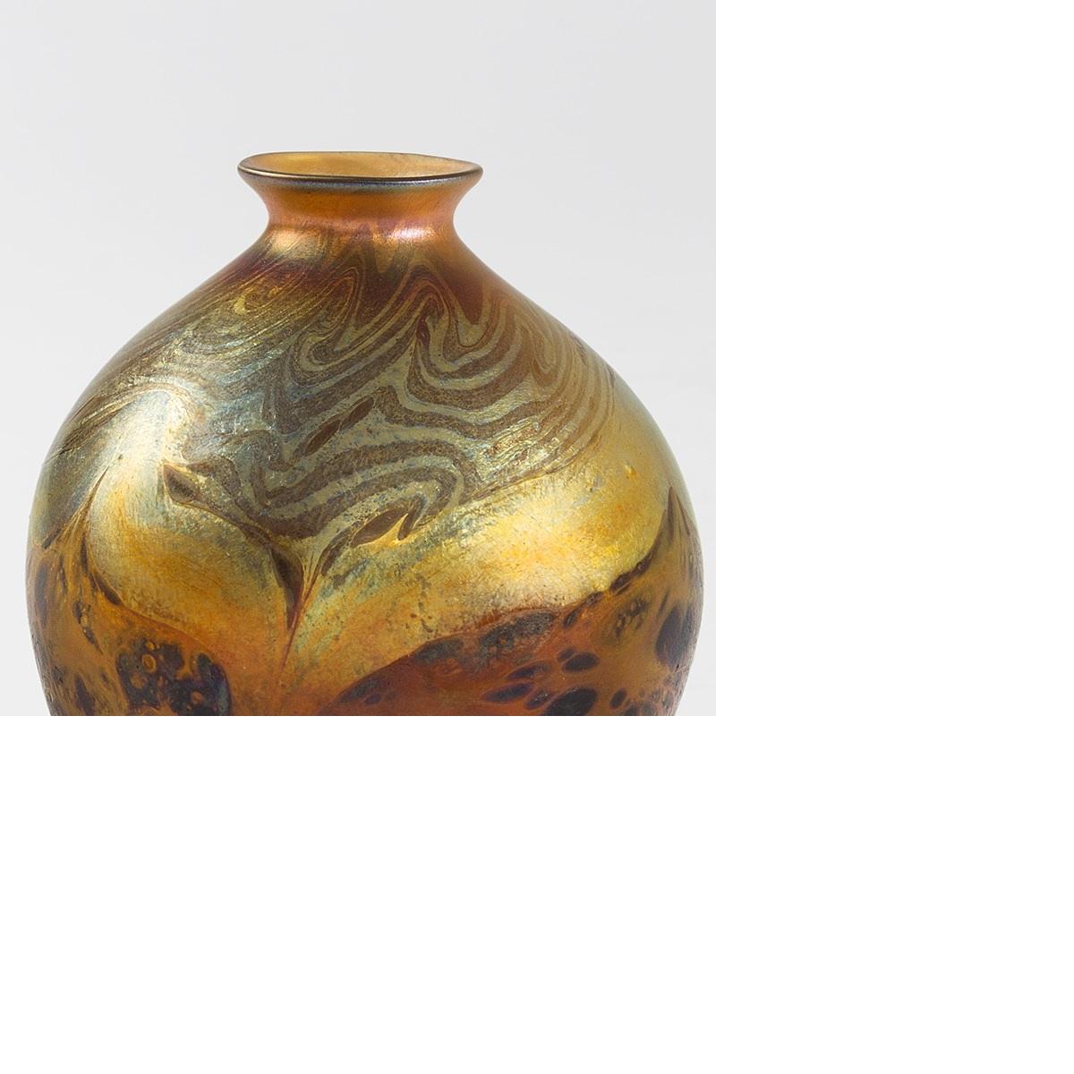 An early and unusual Tiffany Favrile glass Cypriote vase. The rounded body of the vase is decorated near the tapered neck and near the foot with an iridescent swirling motif in richly saturated tones of gold and ochre, framing a series of central