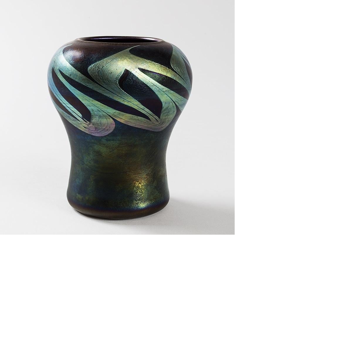 A blue green Favrile glass vase by Louis Comfort Tiffany featuring a pulled silver iridescent border.  Circa 1900's.

Favrile is the trade name Tiffany gave to his blown art glass. The name derives from the Latin word fabrilis, meaning “made by