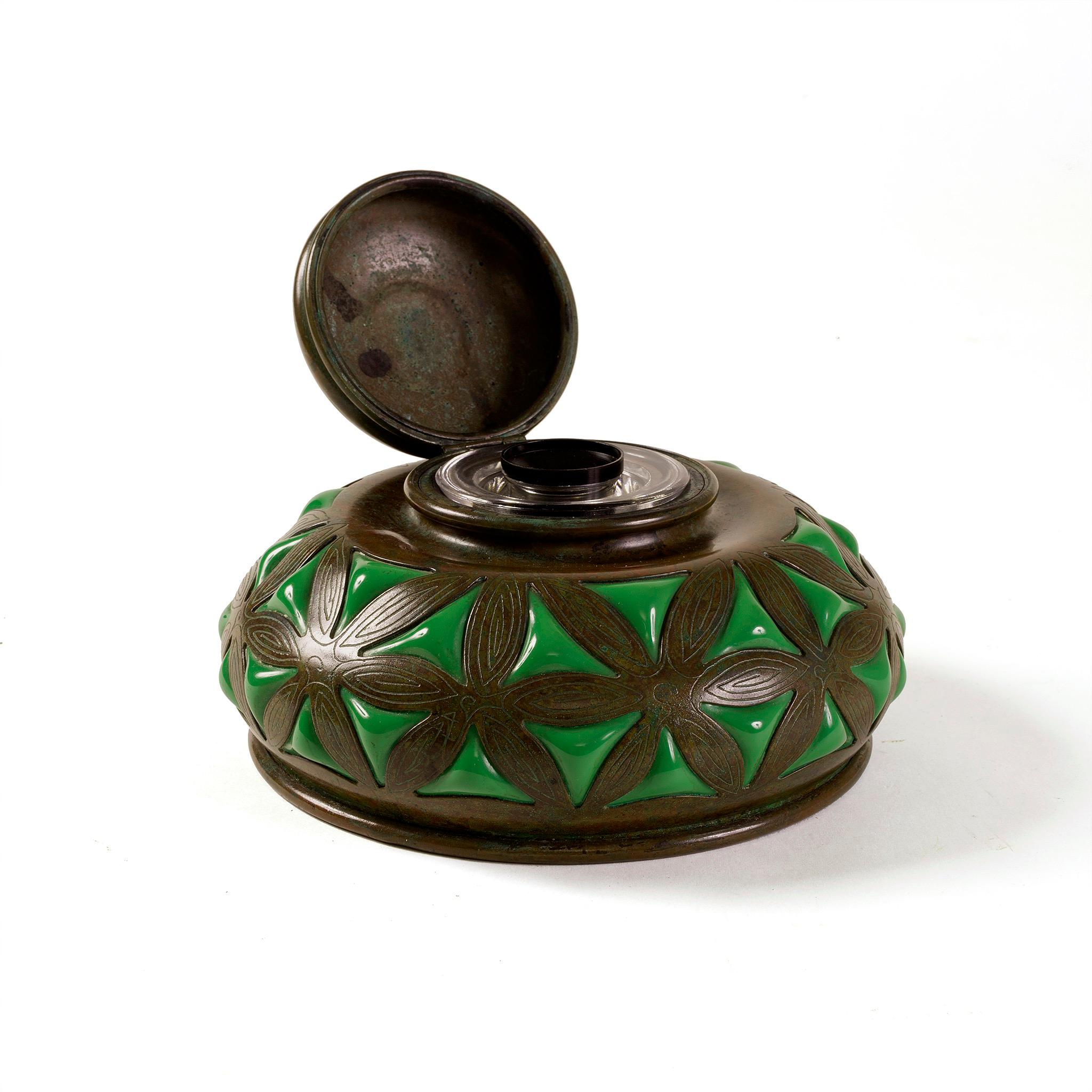 Among the most visually alluring and technically excellent of all Tiffany Studios New York's desk accessories, the exciting design for this refined but robustly rounded inkwell features green blown glass in pinched triangular forms that appear to