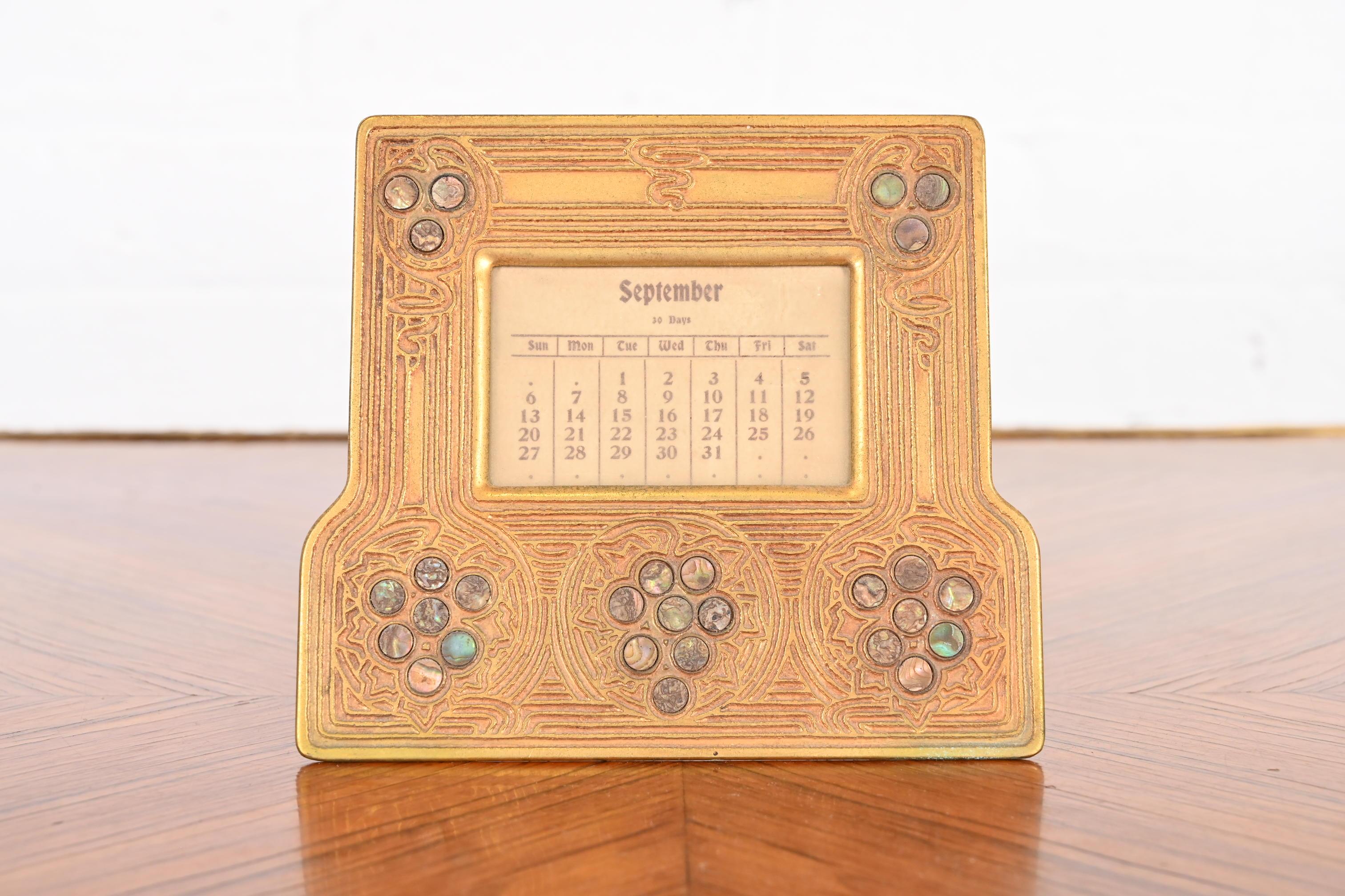 A gorgeous Art Deco period bronze doré and inlaid abalone picture frame or calendar frame with original calendar inserts

By Tiffany Studios

New York, USA, early 20th century

Measures: 6.5
