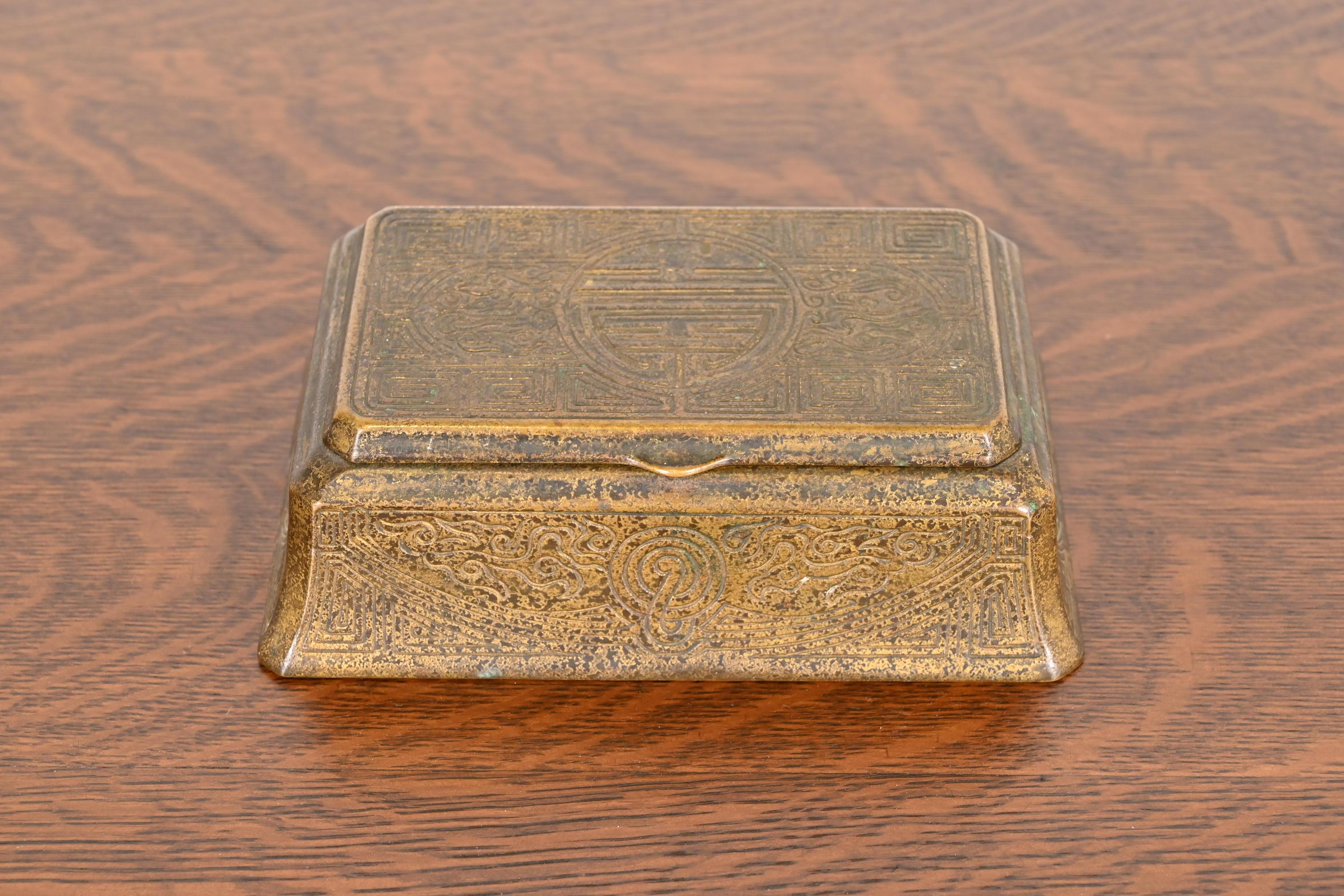 Preciosa caja de escritorio, joyero o caja decorativa antigua de época Arts & Crafts o Art Decó, de bronce dorado con motivos chinos

Por Tiffany Studios (firmado en la parte inferior)

Nueva York, EE.UU., Principios del siglo XX

Medidas: 8 