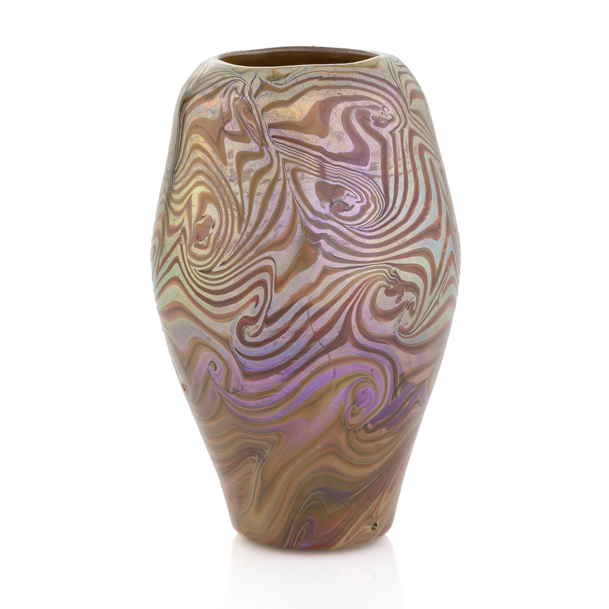 This arresting Damascene Favrile Glass Vase bears a swirling pattern of blue and purple iridescence and ochre glass. The vase's pattern is based upon Damascus steel, whereby near eastern blacksmiths welded iron and high carbon steel, folding the