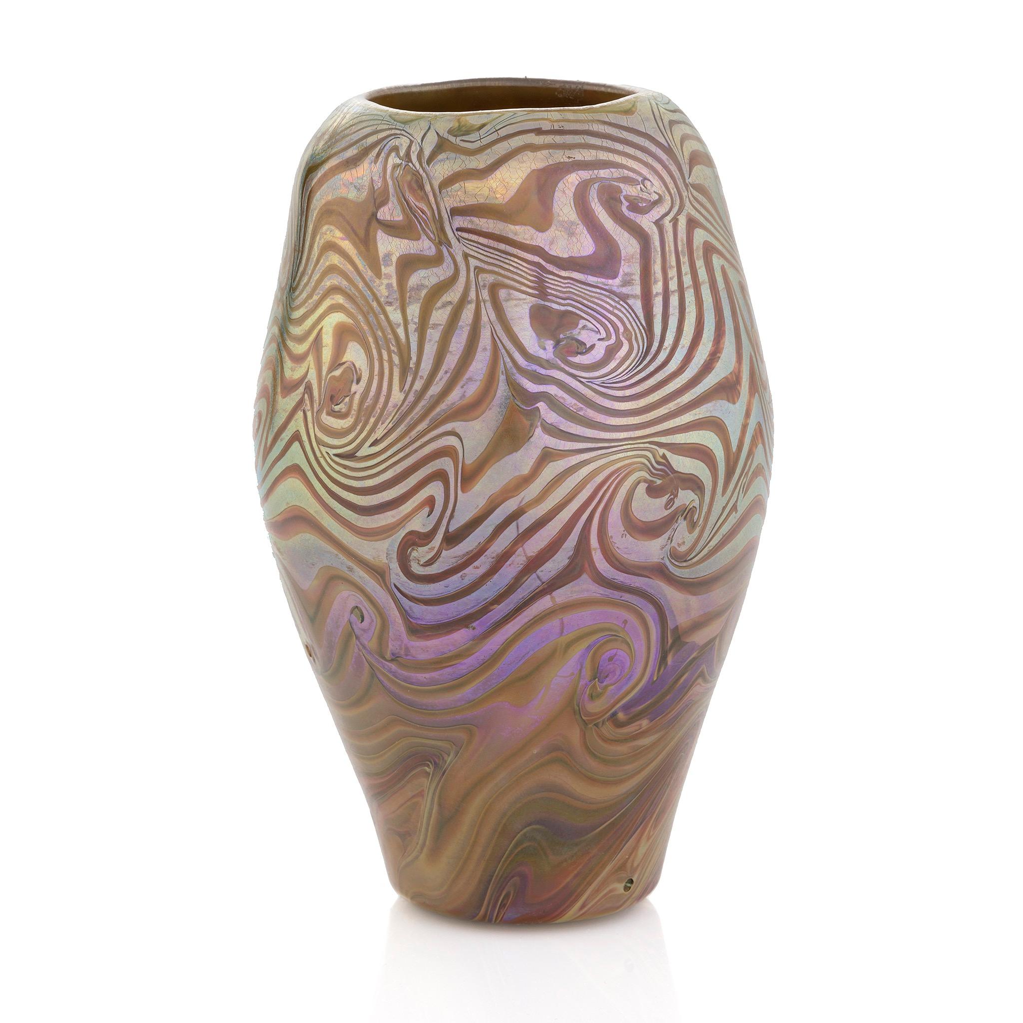 Questo sorprendente vaso in vetro Damasceno Favrile presenta un motivo vorticoso di iridescenze blu e viola e vetro ocra. Il modello del vaso si basa sull'acciaio di Damasco, con cui i fabbri del Vicino Oriente saldavano ferro e acciaio ad alto