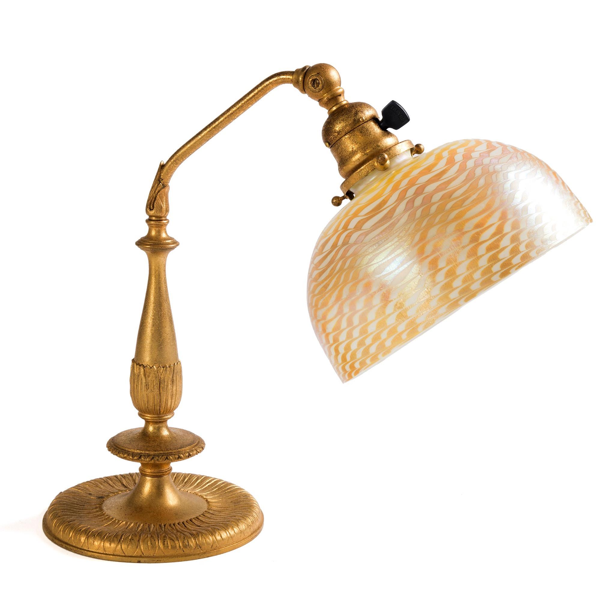 This delicately sized Tiffany Studios New York “Damascene” lamp is superbly colored in blood-orange and gold. Trails of blood orange glass were applied obliquely then combed through to create a stunning waved pattern. The Damascus lamps were named