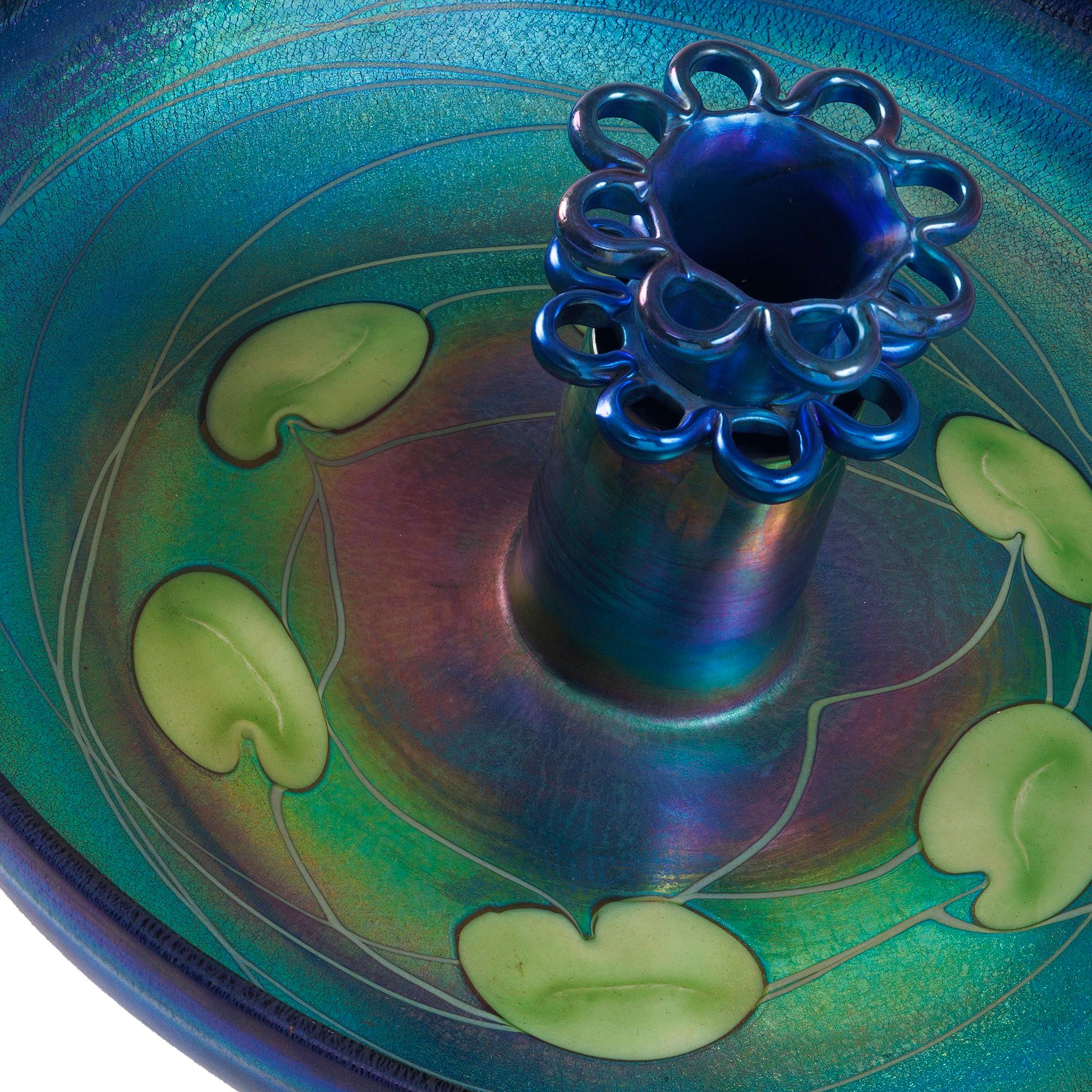 This Tiffany Studios New York centerpiece, features deep-blue green iridescent Favrile glass, decorated with a iridescent green leaf and vine decoration. The charming piece features only the brightest coloration of turquoise blue imbued with
