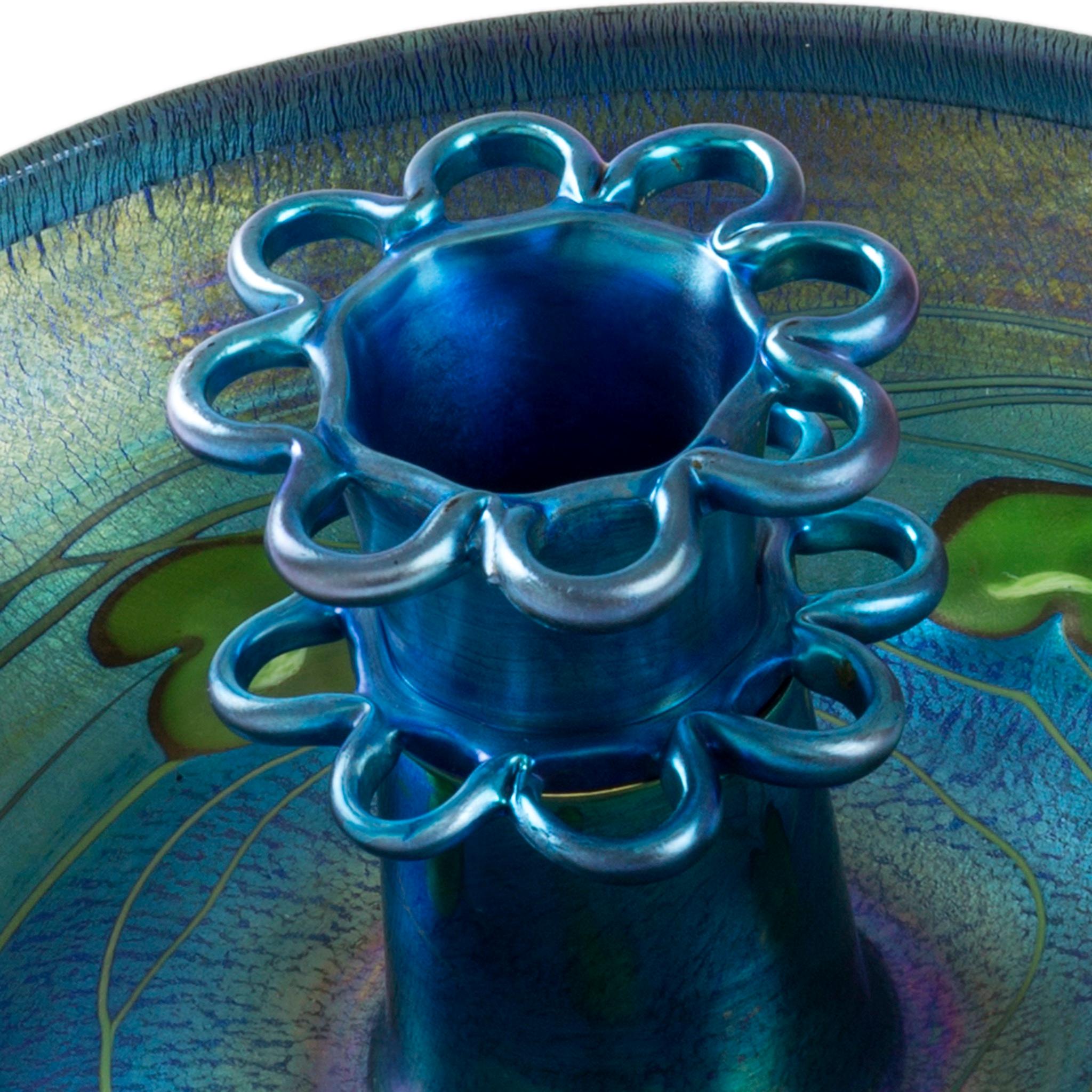 Questo centrotavola di Tiffany Studios New York è caratterizzato da un vetro Favrile iridescente verde-blu intenso, decorato con una foglia e una vite verde iridescente. L'affascinante pezzo presenta solo le colorazioni più brillanti del blu