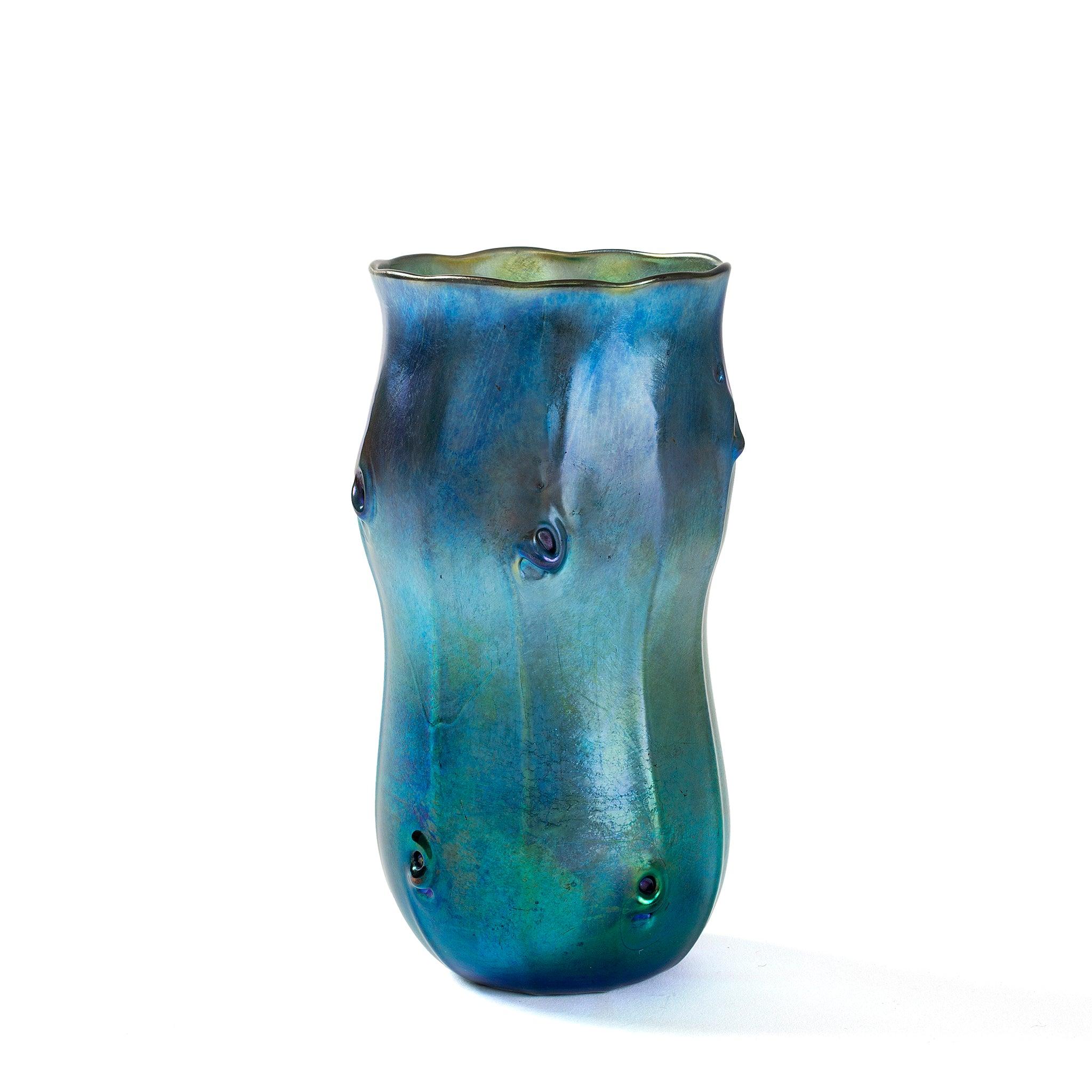 This Tiffany Studios New York blue Favrile glass vase is a stylized Art Nouveau version of the Chinese huluping or double-gourd vase. The vase is decorated with fluting and swirled pigtail prunts that recall the lapping of ocean waves, grating from