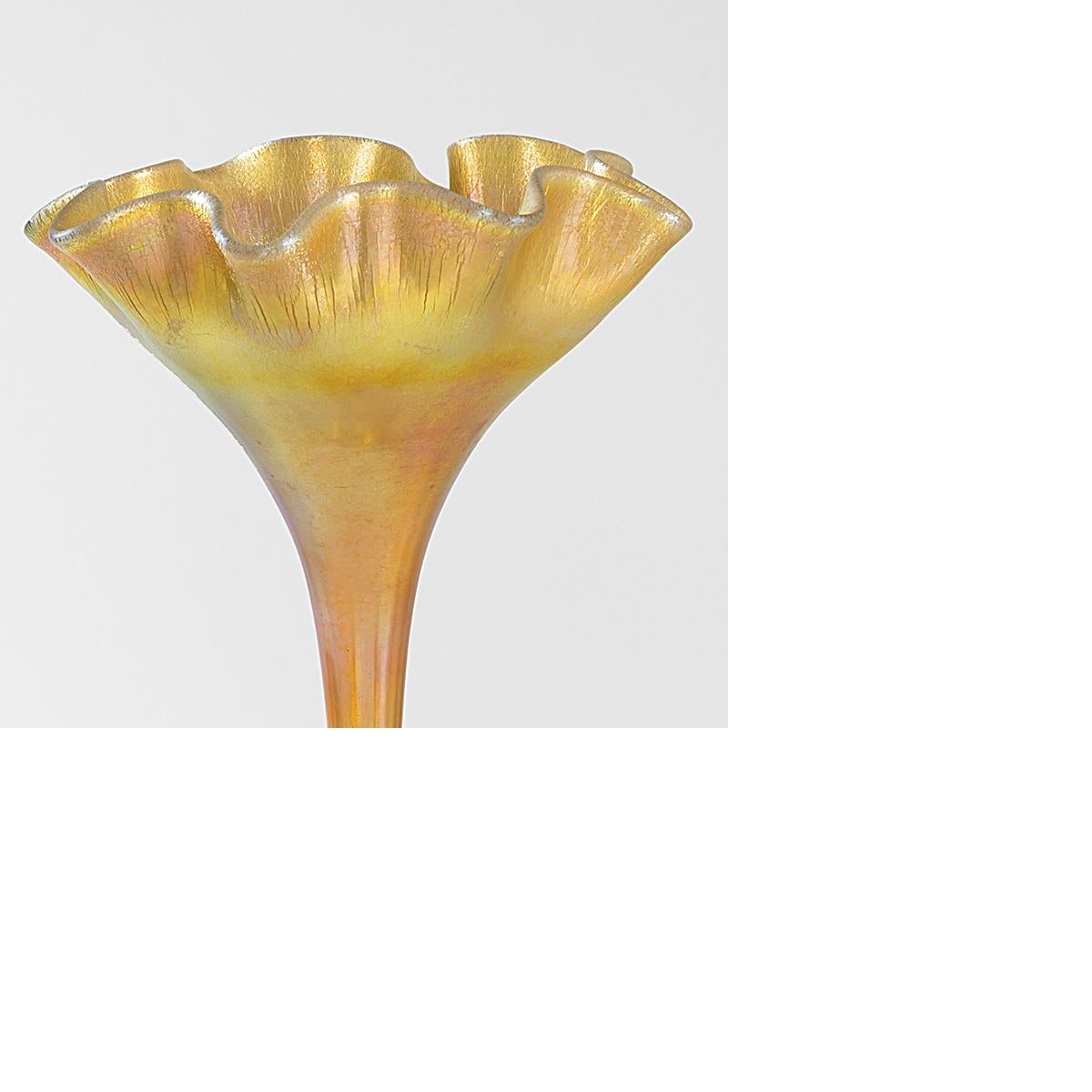 A Tiffany Studios New York iridescent gold Favrile ruffled floriform glass vase.   This vase is unusual both for its size and for its bulbous foot, seen more often in Tiffany's Jack-in-the-Pulpit vases than his floriform vases.  Circa 1900.