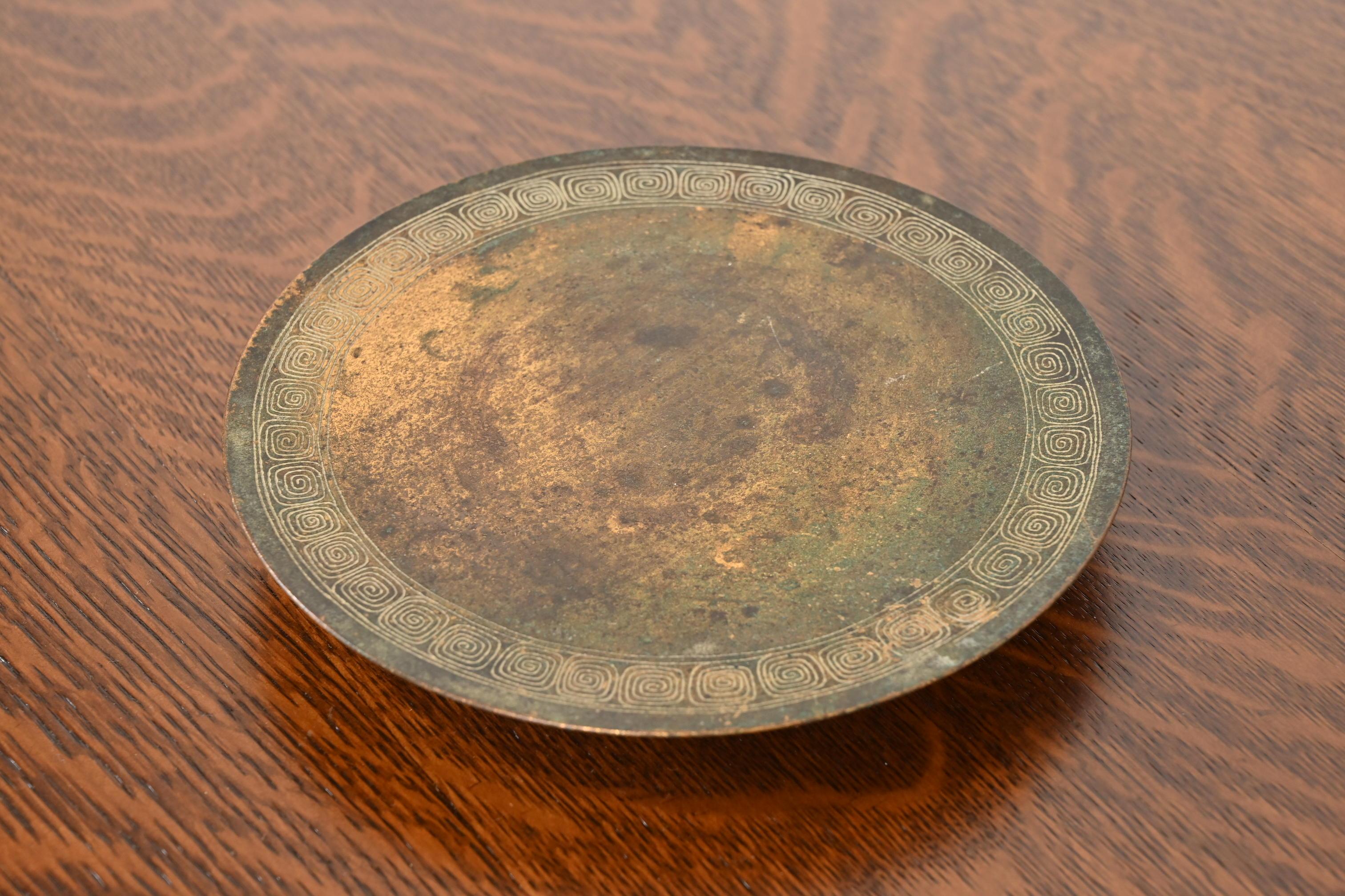 Magnifique plateau de service ou assiette à pied en bronze d'époque Arts & Crafts ou Art Deco avec un motif de clé grecque.

Par Tiffany Studios (signé sur le dessous)

New York, États-Unis, Début du XXe siècle

Dimensions : 8 