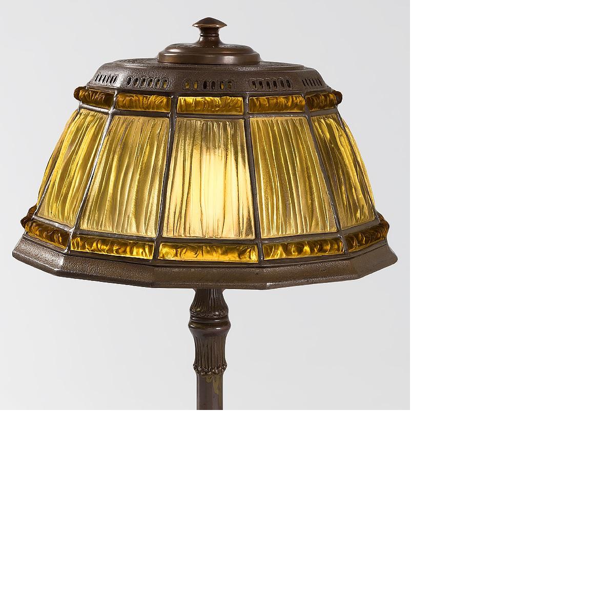 A Tiffany Studios New York glass bronze “Linenfold” lamp, featuring a Favrile glass golden yellow “Linenfold” shade with gilt leading. The shade sits atop a patinated bronze base, circa 1900.

A similar lamp is pictured in: Alastair Duncan,