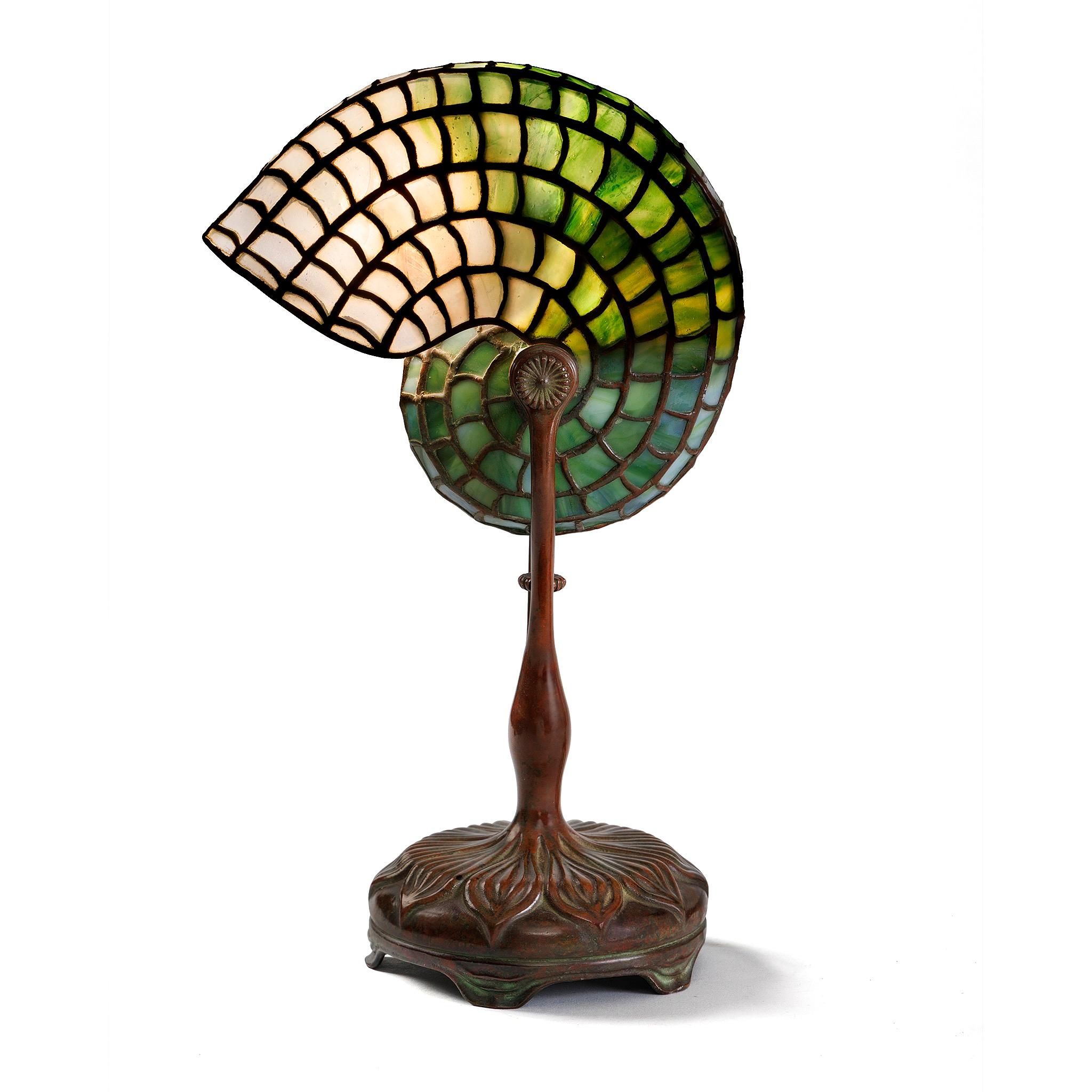 A natural form captured masterfully in regular glass paneling, the shade of this Tiffany Studios New York lamp graduates from emerald green to a clean off-white as it unfurls, mimicking the shape of a nautilus shell. The shade tapers significantly