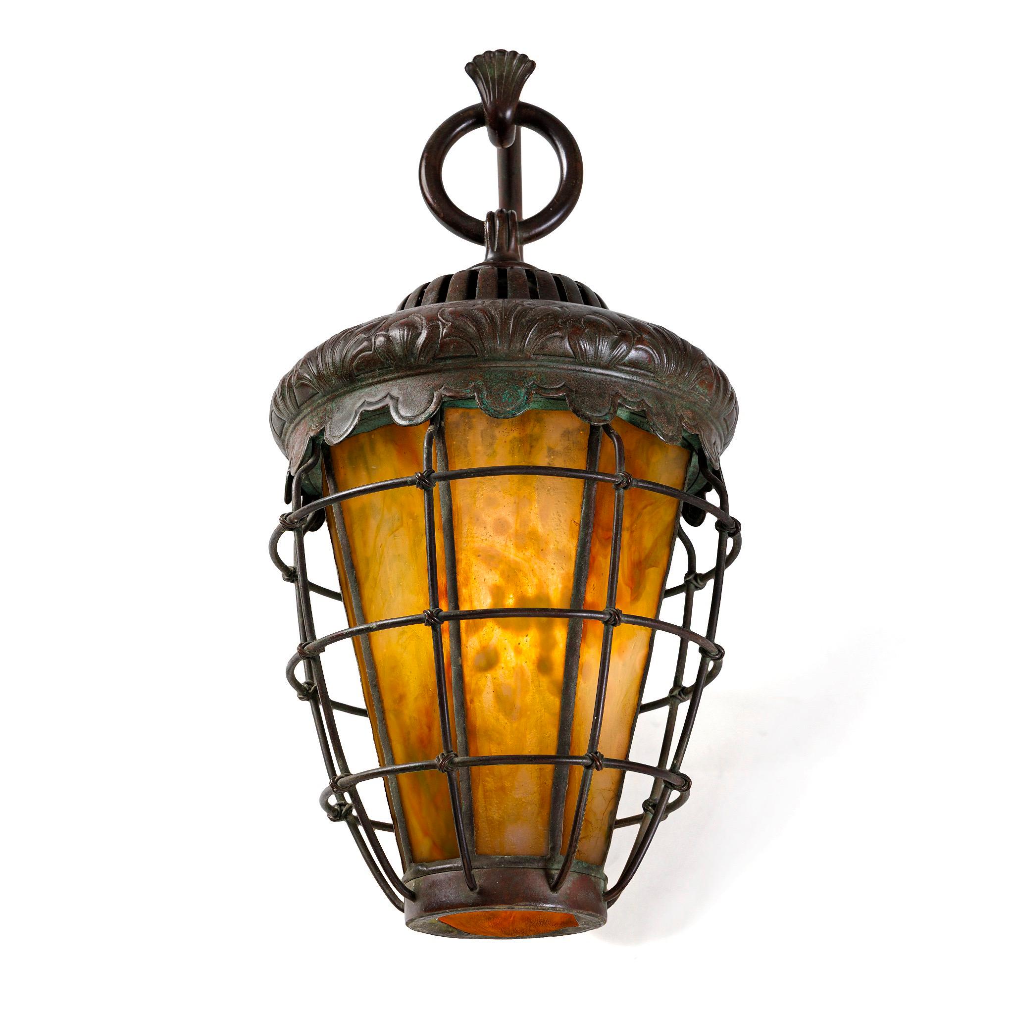 This refined pair of caged lantern sconces features leaf-shaped backplates adorned with elegant palmette hooks. The heat caps are encircled by a decorative frieze of flame-like palmettes, adding a dynamic sense of movement to the design. Each yellow