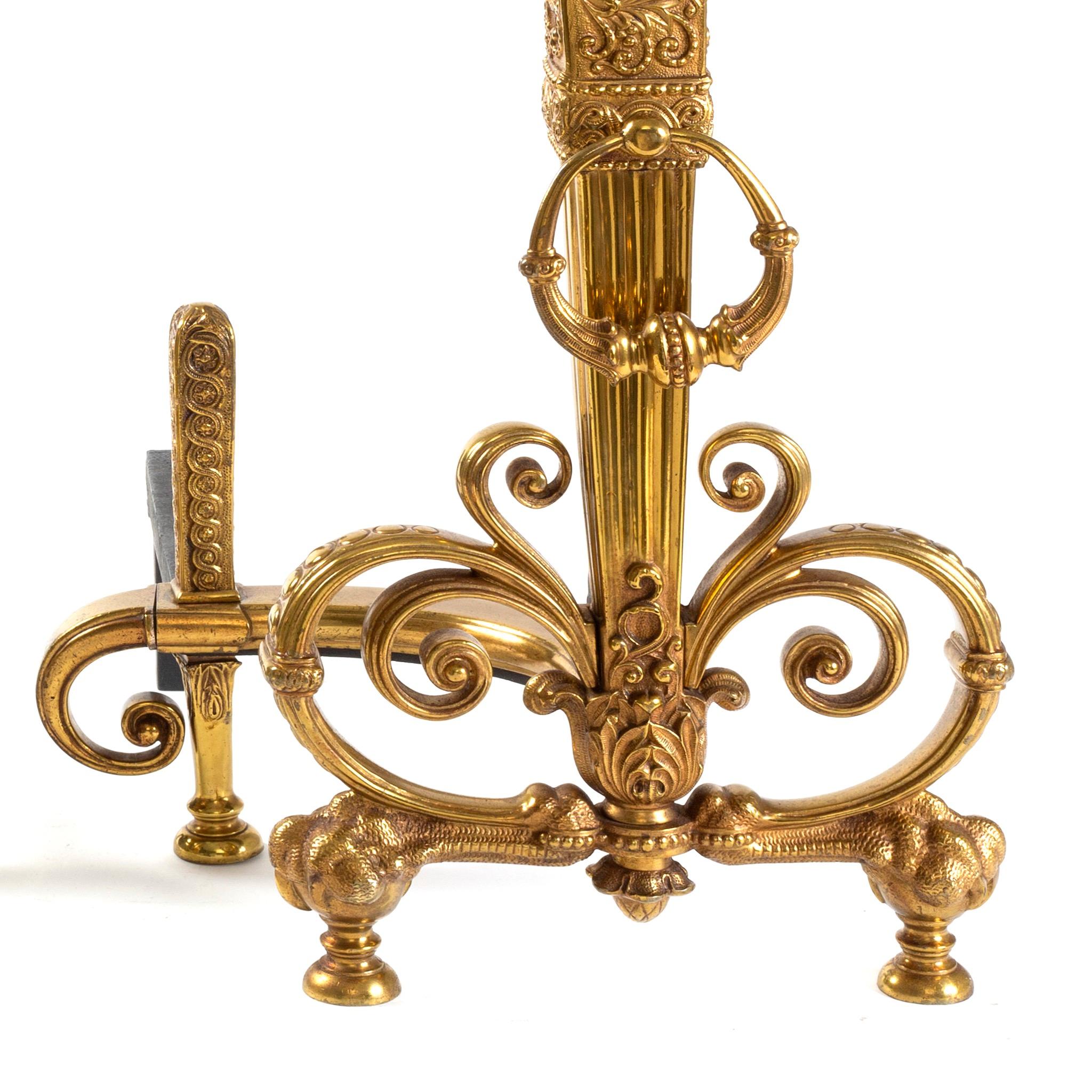 This pair of Tiffany Studios New York andirons in gilt bronze features French baroque style openwork decoration framing at their bases, with cast decoration that was made to imitate the most intricate and beautiful of Celtic strapwork. At age