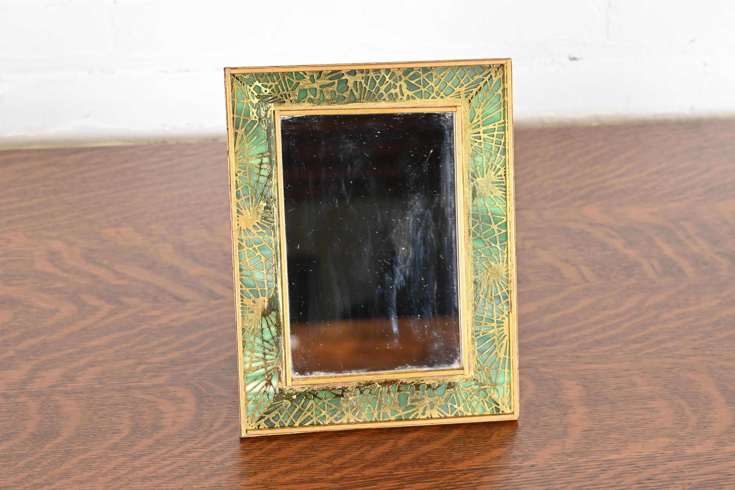 Un raro y excepcional espejo antiguo de época Arts & Crafts con marco de agujas de pino

Por Tiffany Studios (firmado en el reverso)

Nueva York, EE.UU., Principios del siglo XX

Bronce dorado en icónico diseño de agujas de pino, con hermoso cristal