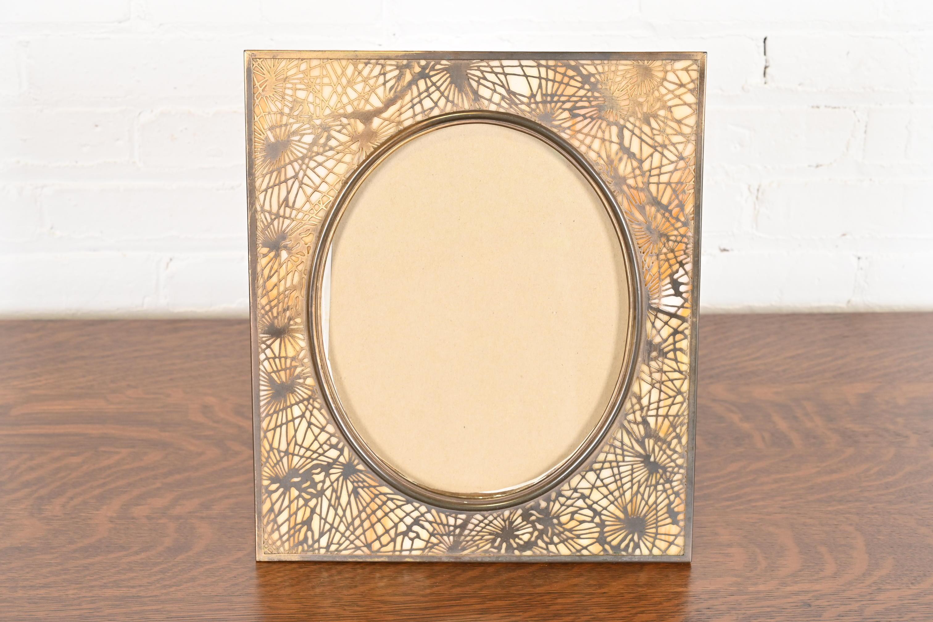 An exceptional antique Arts & Crafts period large picture frame

By Tiffany Studios

New York, USA, Early 20th Century

Gilt bronze in iconic pine needle pattern, with beautiful slag glass.

Measures: 12