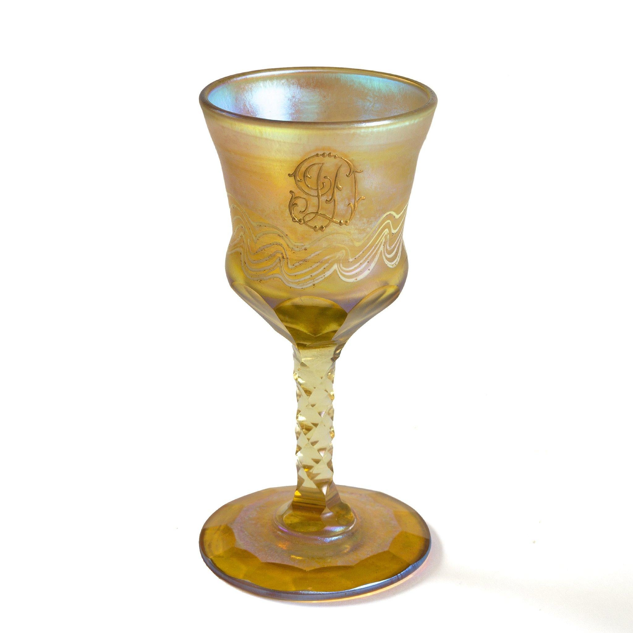 Two cups of intricate design and six cordials glasses make up this set by Tiffany Studios New York. 

All in golden hues, the receptacles are imbued with radiant flashes of iridescence, so as to delight from every angle. While the cordial glasses