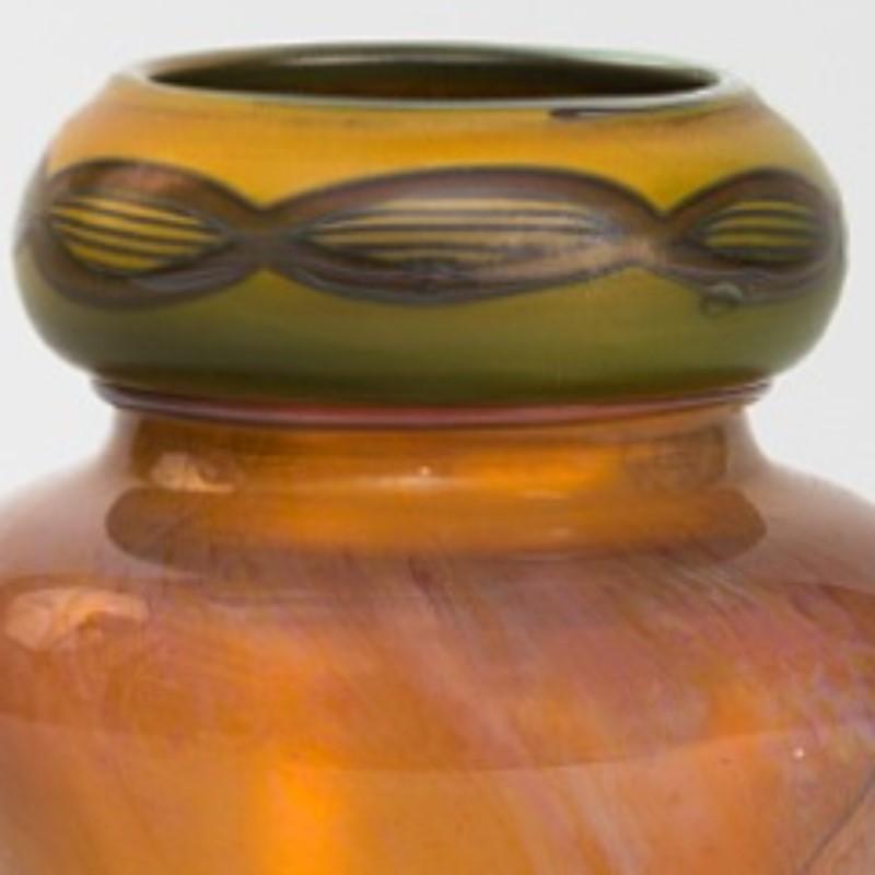 A Tiffany Studios New York glass vase. A wide-shouldered, unique translucent gold body with a band of green colored Egyptian-inspired “Tel-El-Amarna” design around the neck. 

A vase with similar decoration is pictured in: Tiffany at Auction, by