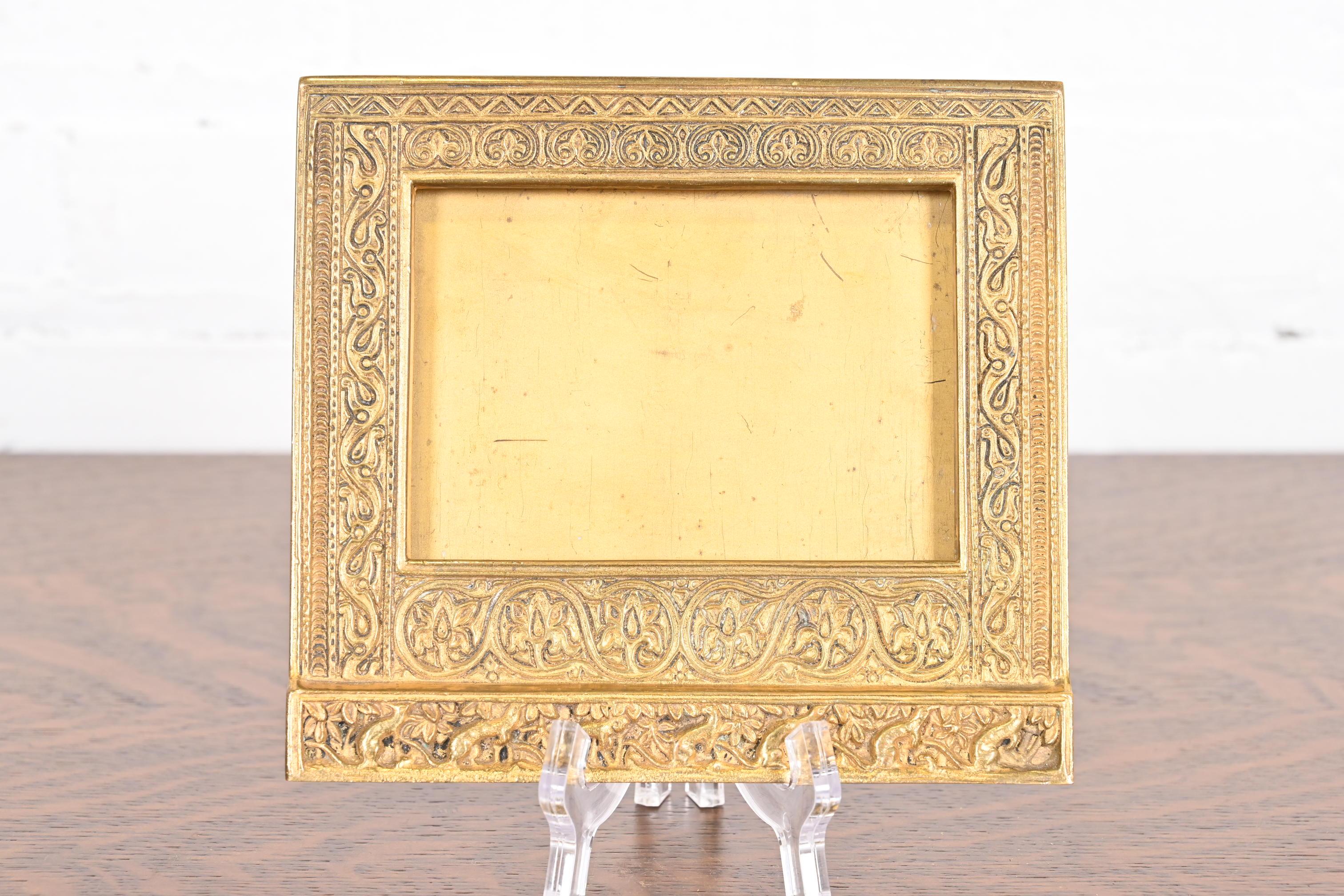 Un precioso marco de calendario de escritorio o marco de fotos antiguo de bronce dorado con motivos venecianos

Por Tiffany Studios (firmado al dorso)

Nueva York, EE.UU., Principios del siglo XX

Medidas: 6,5 
