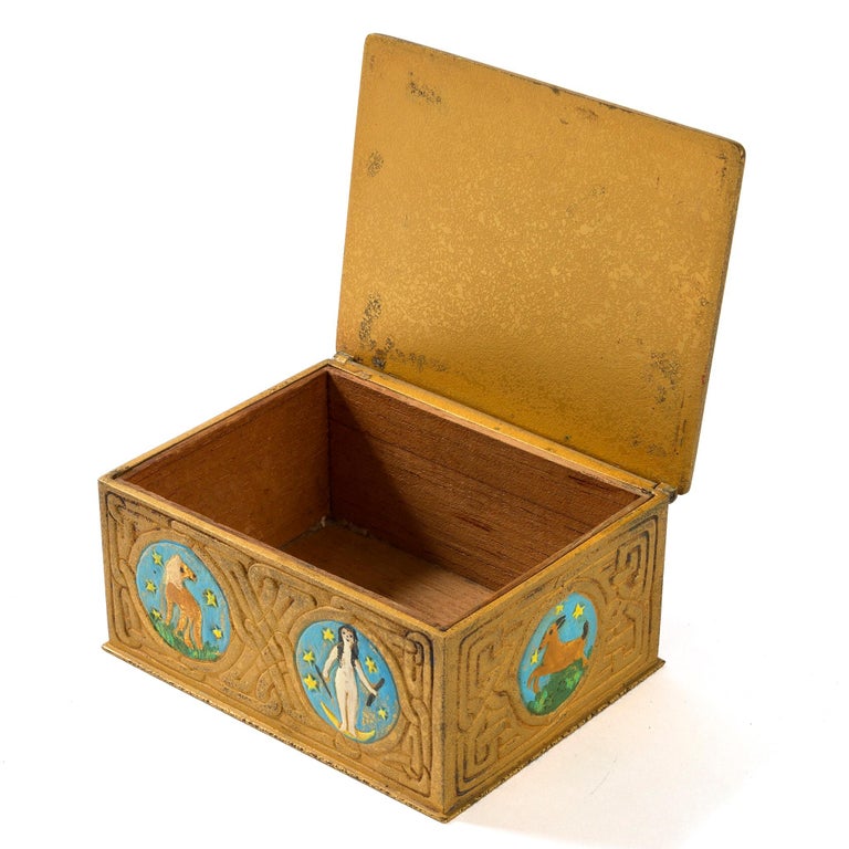 A gilt bronze “Zodiac” box by Tiffany Studios New York. The box features intricate pseudo-Celtic patterning interspersed with circular elements in sky blue, each of which features a stylized depiction of one of the 12 signs of the Zodiac, all