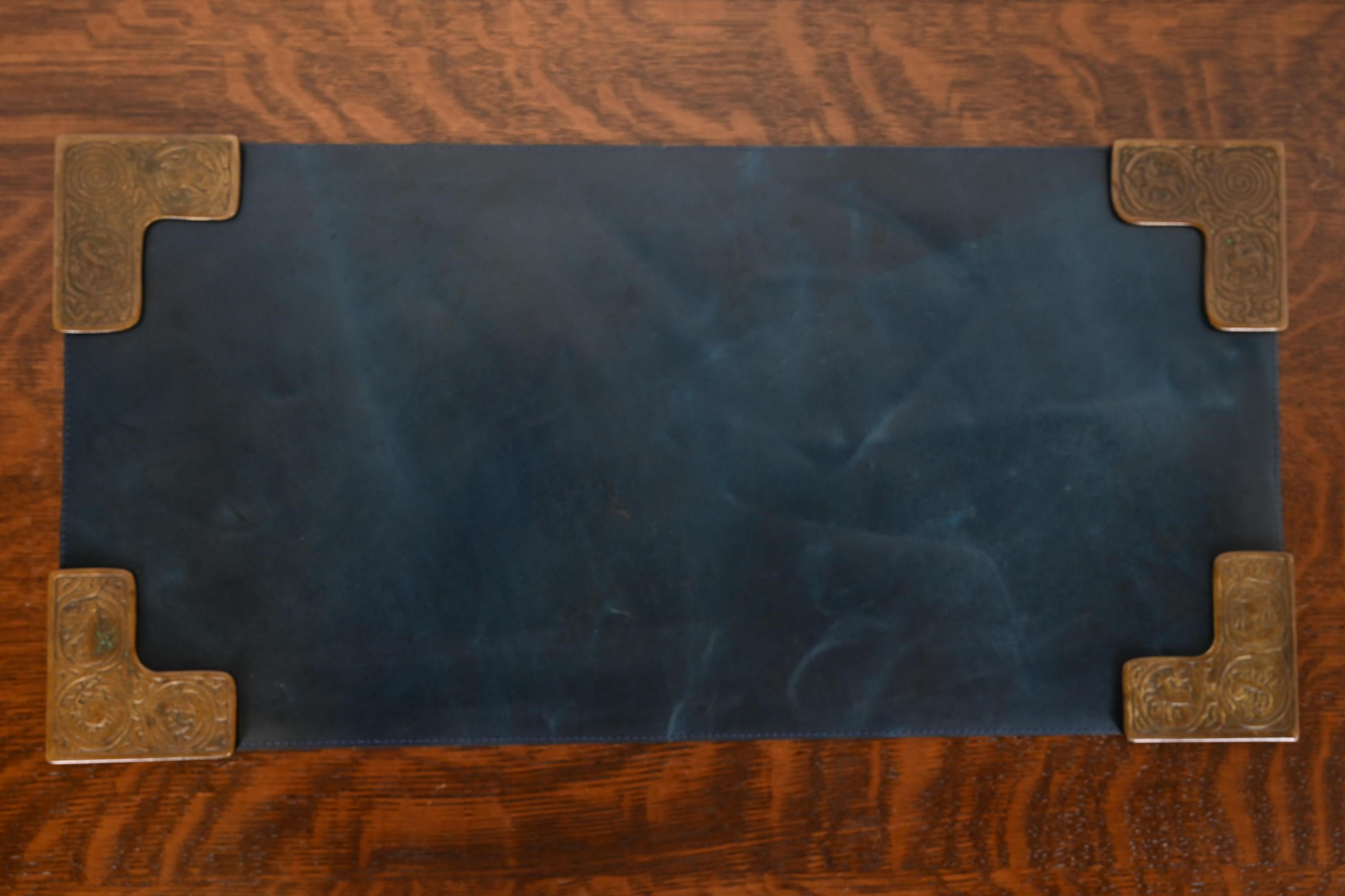 A gorgeous set of four Art Deco or Arts & Crafts period bronze blotter corners featuring symbols of the Zodiac, with a custom blue leather desk blotter.

By Tiffany Studios (blotter corners signed to the underside)

New York, USA, Early 20th