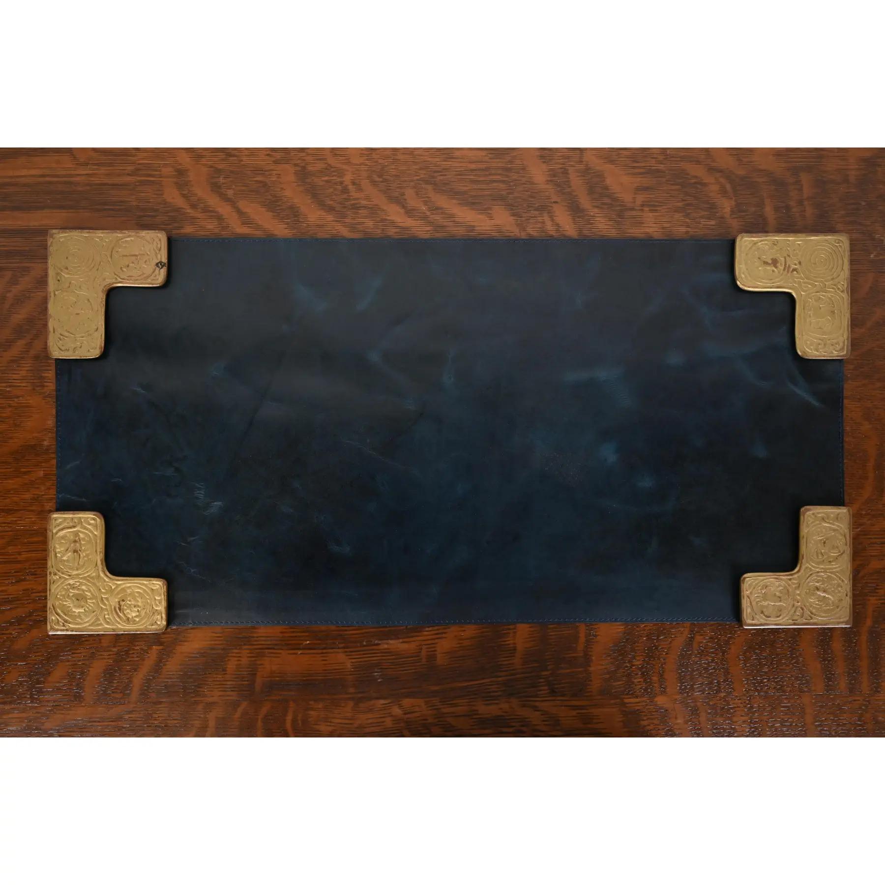 A gorgeous set of four Art Deco or Arts & Crafts period gilt bronze blotter corners featuring symbols of the Zodiac, with a custom blue leather desk blotter.

By Tiffany Studios (blotter corners signed to the underside)

New York, USA, Early 20th
