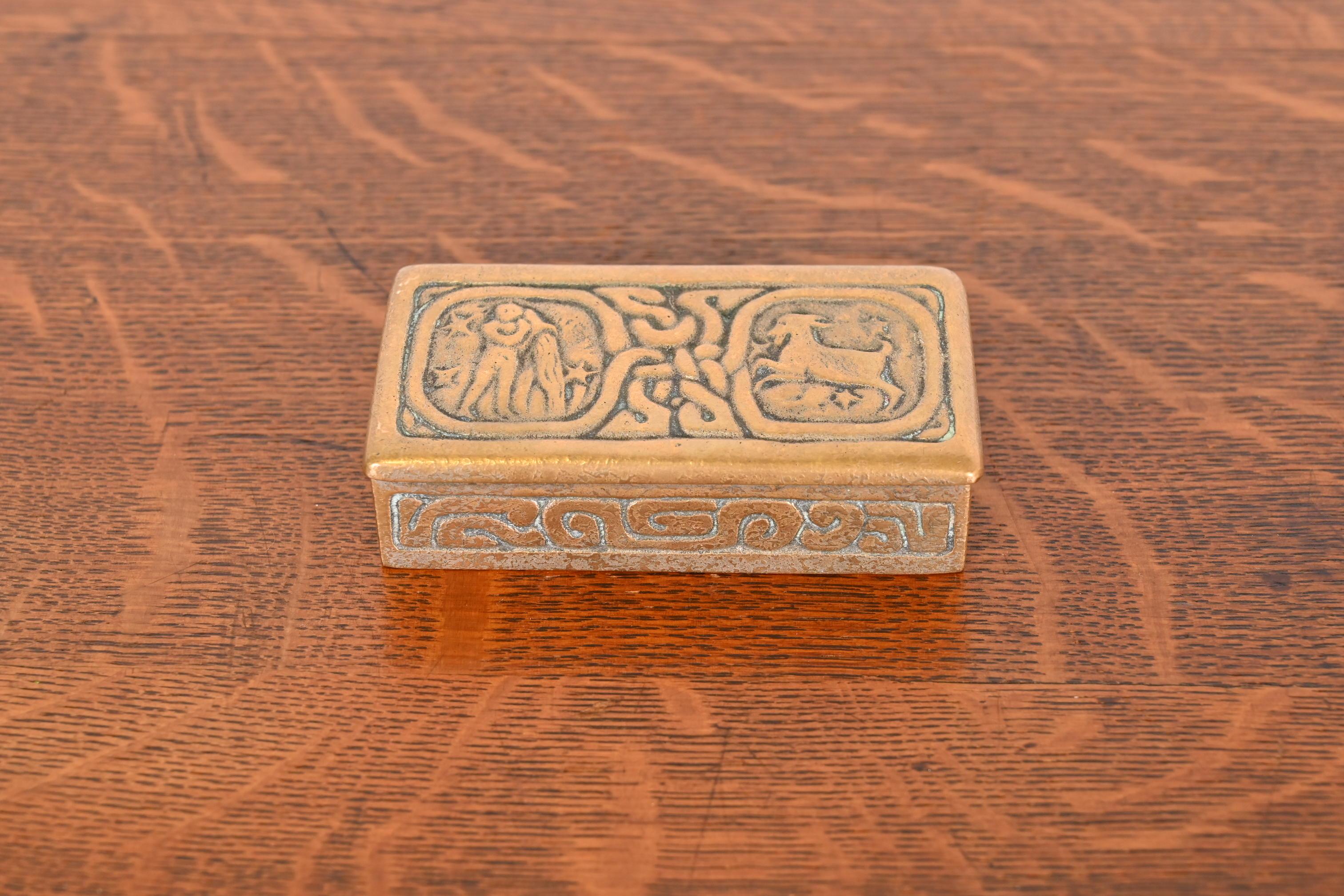 Une superbe boîte à timbres ancienne en bronze doré avec des motifs de Zodiac.

Par Tiffany Studios (signé sur le dessous)

New York, États-Unis, Début du XXe siècle

Dimensions : 3,75 