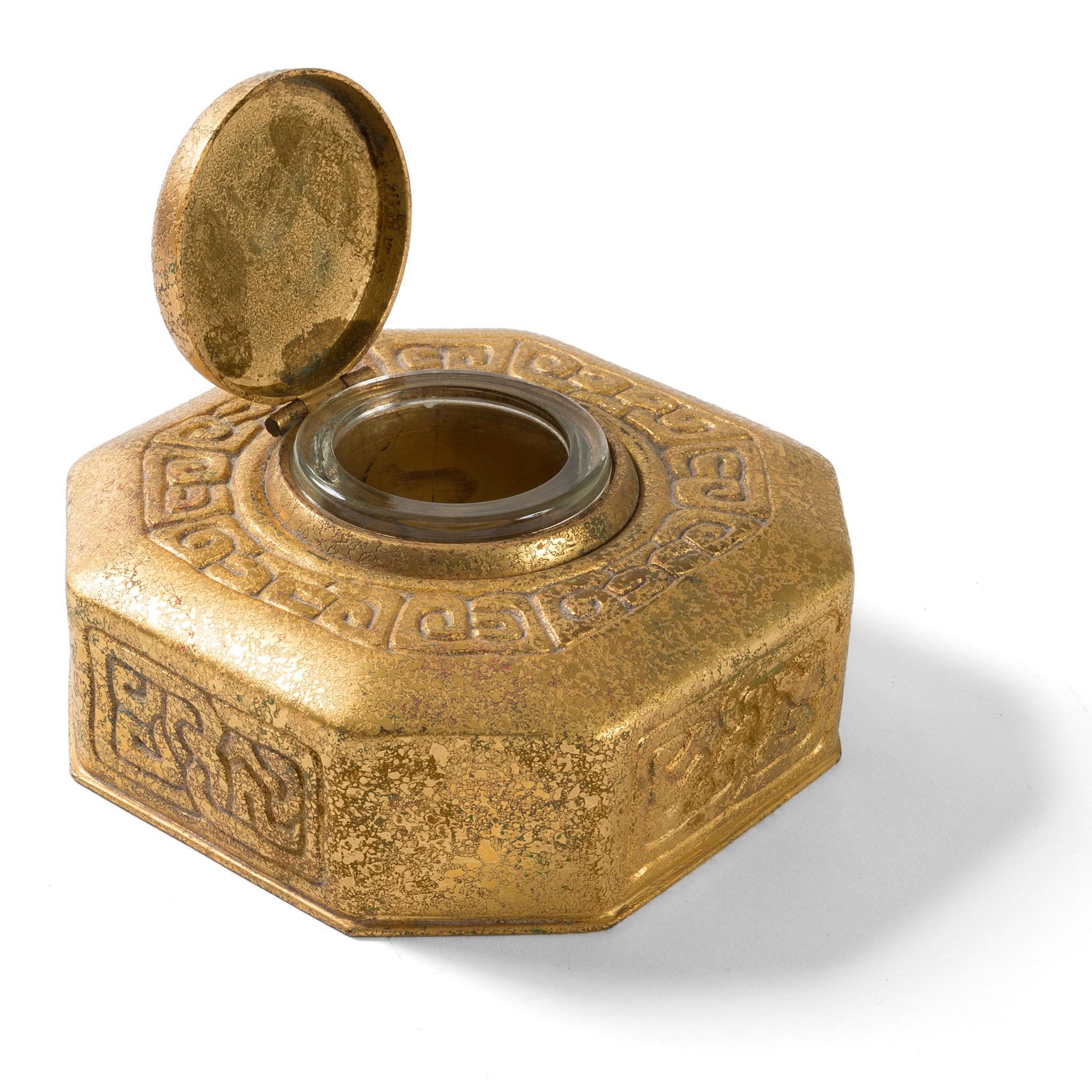 A gilt bronze “Zodiac” inkwell by Tiffany Studios New York. The inkwell features intricate pseudo-Celtic patterning interspersed with circular elements in sky blue, each of which features a stylized depiction of one of the 12 signs of the Zodiac,