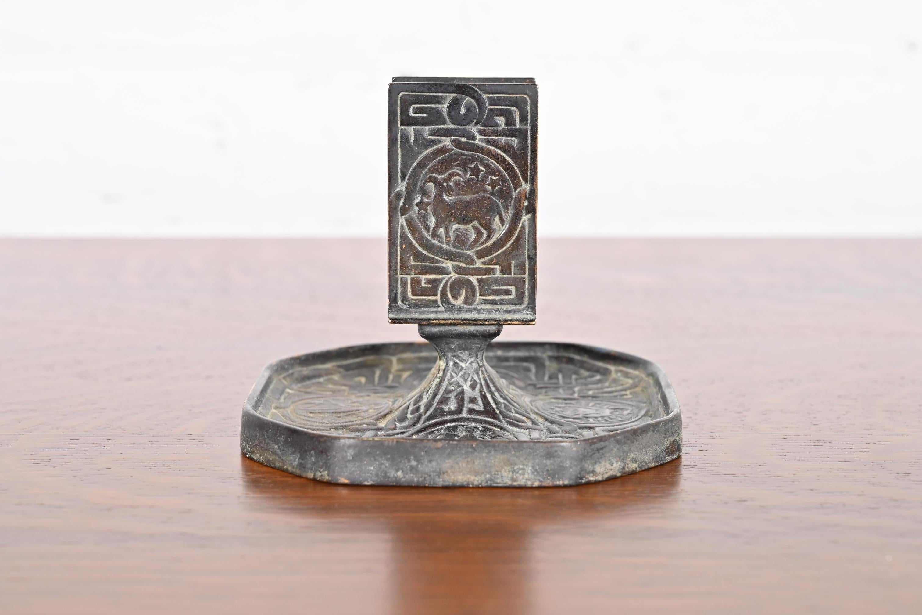 A gorgeous Art Deco period patinated bronze match box holder featuring symbols of the Zodiac

By Tiffany Studios

New York, USA, early 20th century

Measures: 4.5