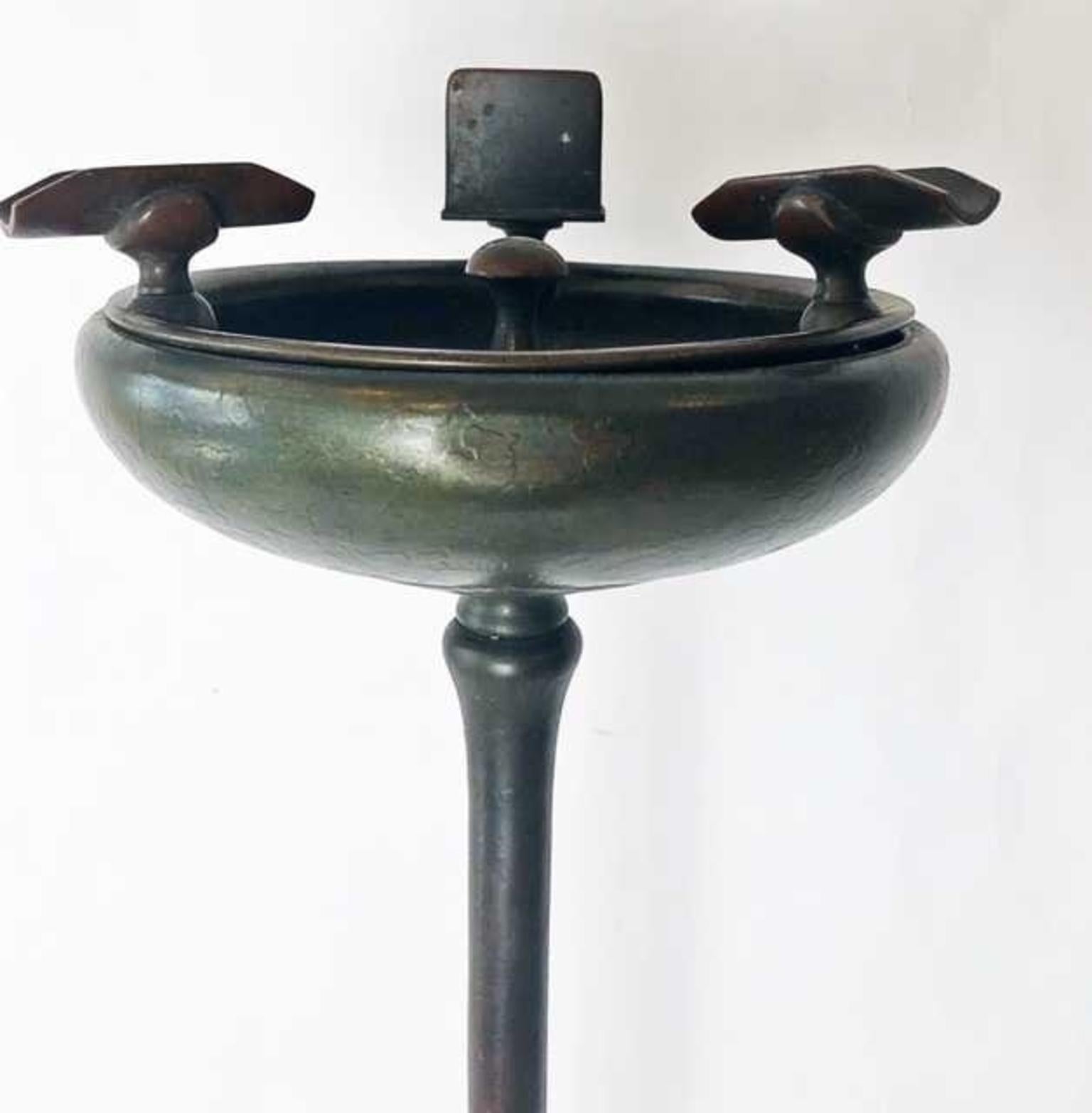 Tiffany Studios patinated bronze standing ash receiver 
Marked Tiffany Studios, 1640.
The columnar stem with circular spreading foot, beneath a deep dish with cigar and a match box holder. 
Measures: Height 27 1/2 in.